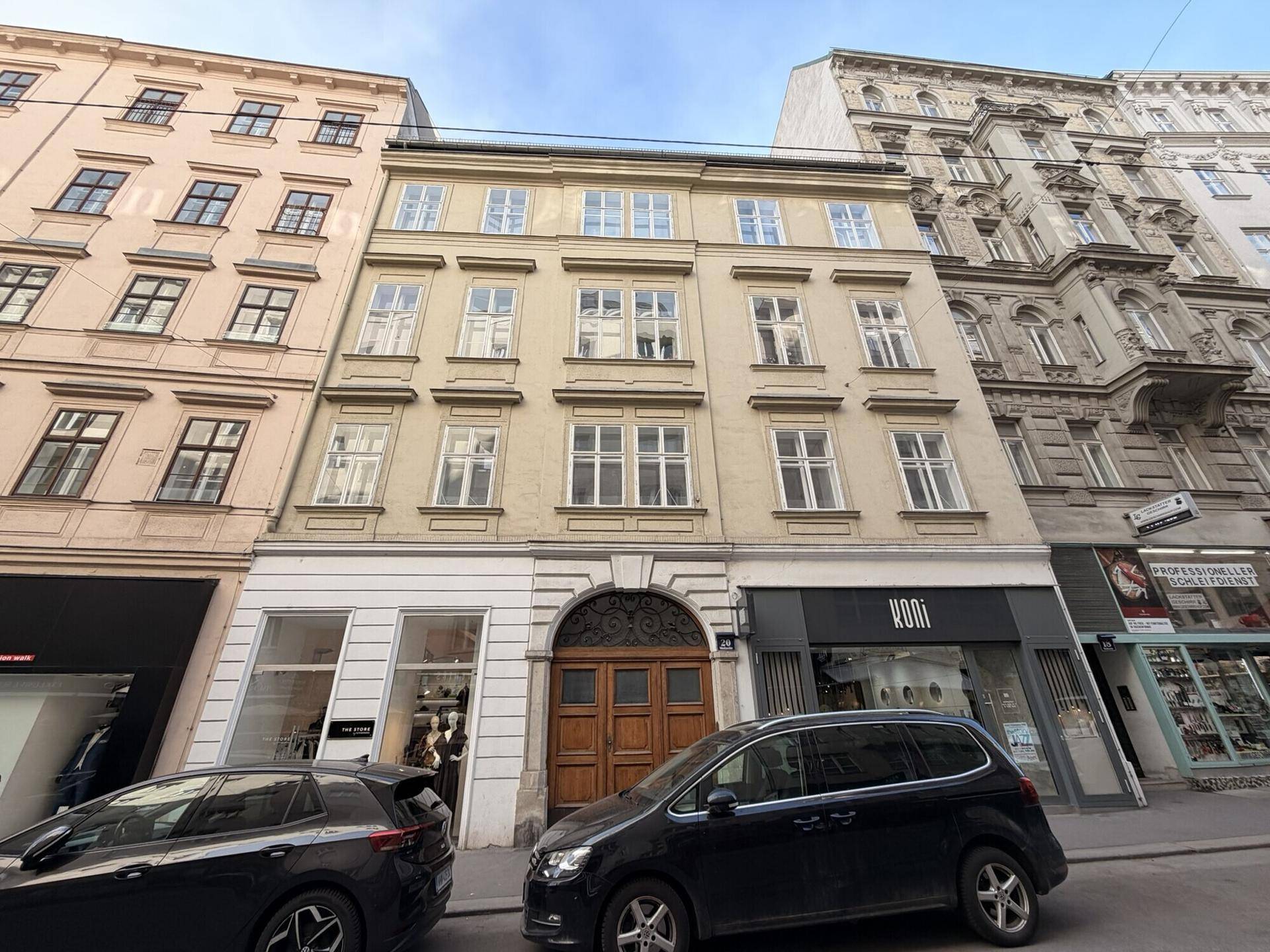 Historisches Gebäude mit klassischer Fassade und vielen Fenstern in einer belebten Stadtstraße.