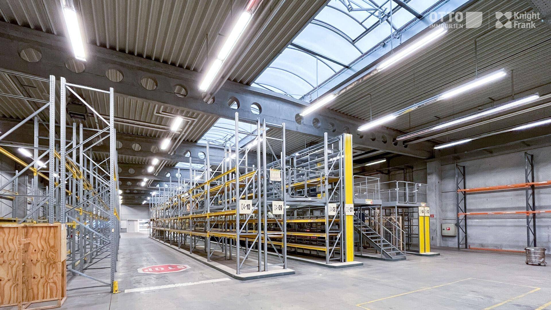 Lagerhalle mit hohen Regalsystemen, Betonboden und Oberlichtern für effiziente Lagerung und Kommissionierung.