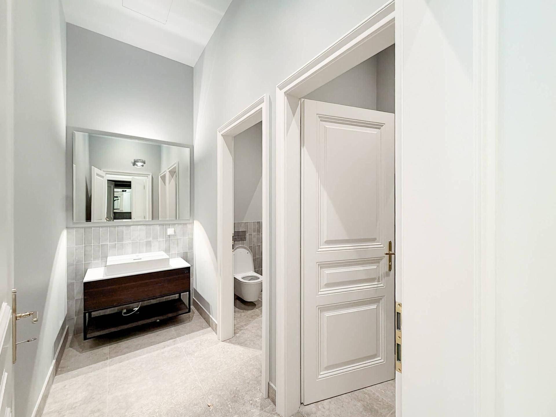 Modernes Badezimmer mit grau gefliesten Wänden, stilvollem Waschtisch und separater Toilette in hellem Design.