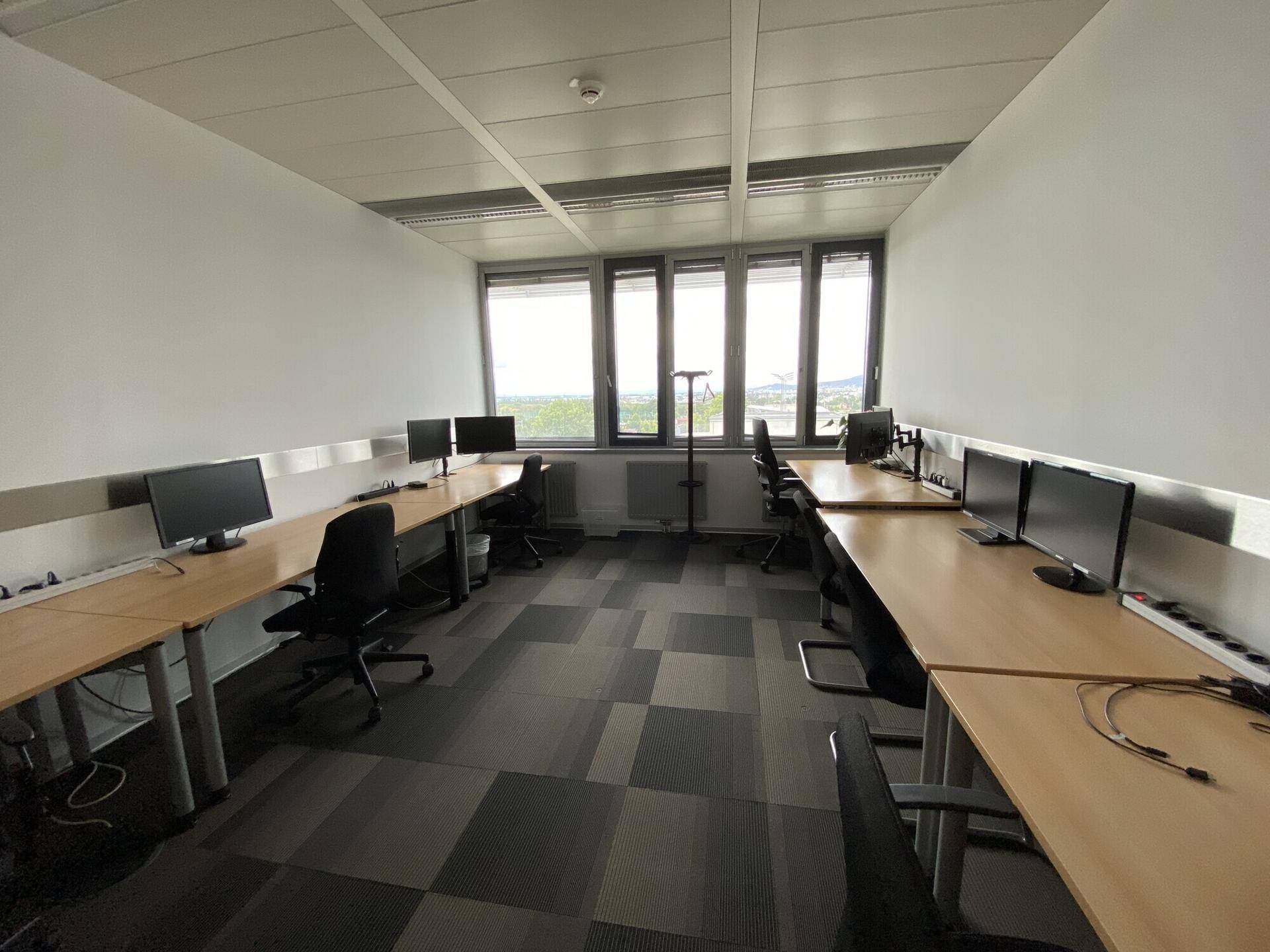 Helles Büro mit ergonomischen Stühlen und Blick ins Grüne durch die Fensterfront.