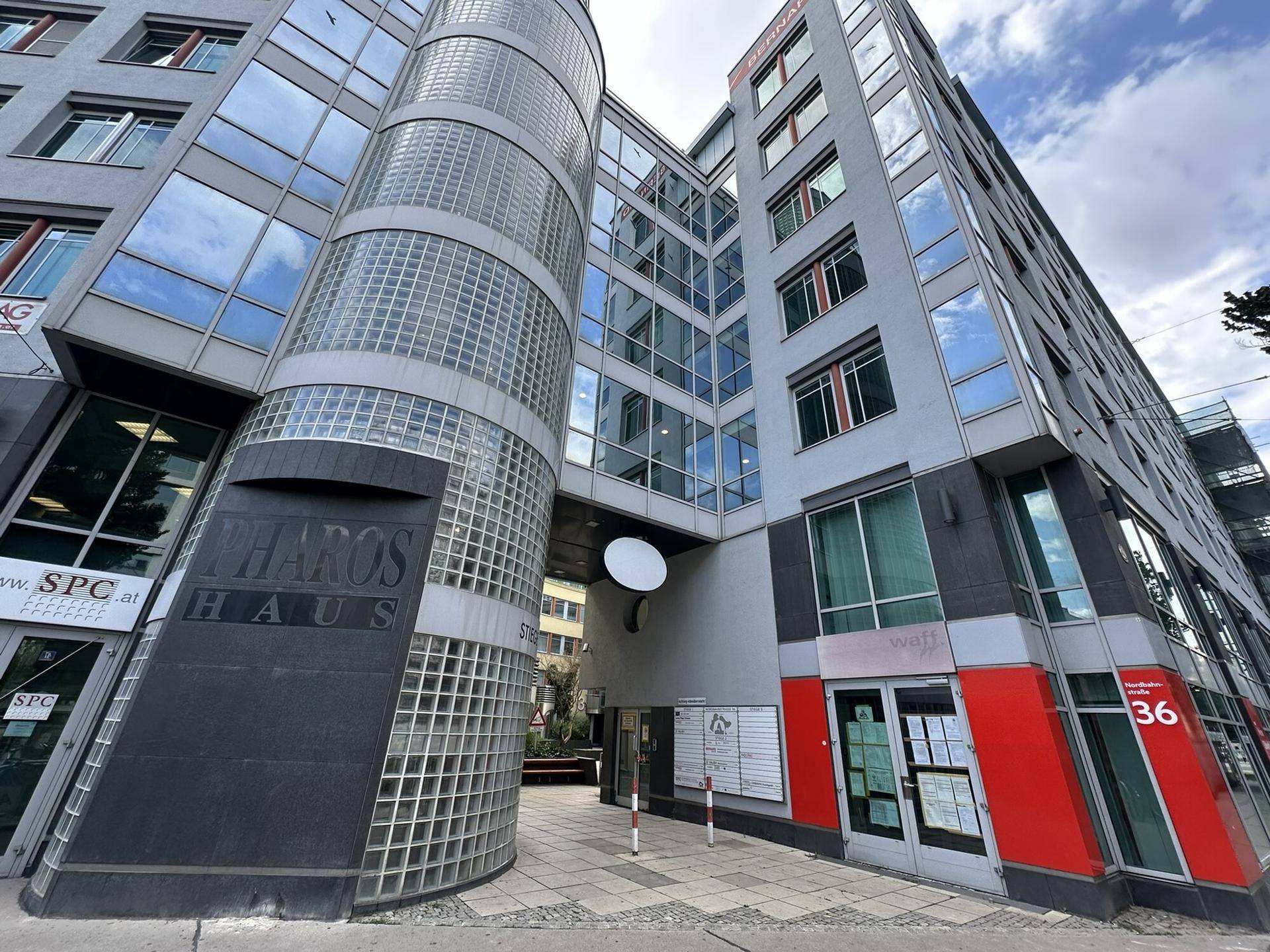 Moderne Bürogebäude-Fassade mit Glas- und Steinelementen sowie einem markanten runden Glasturm.
