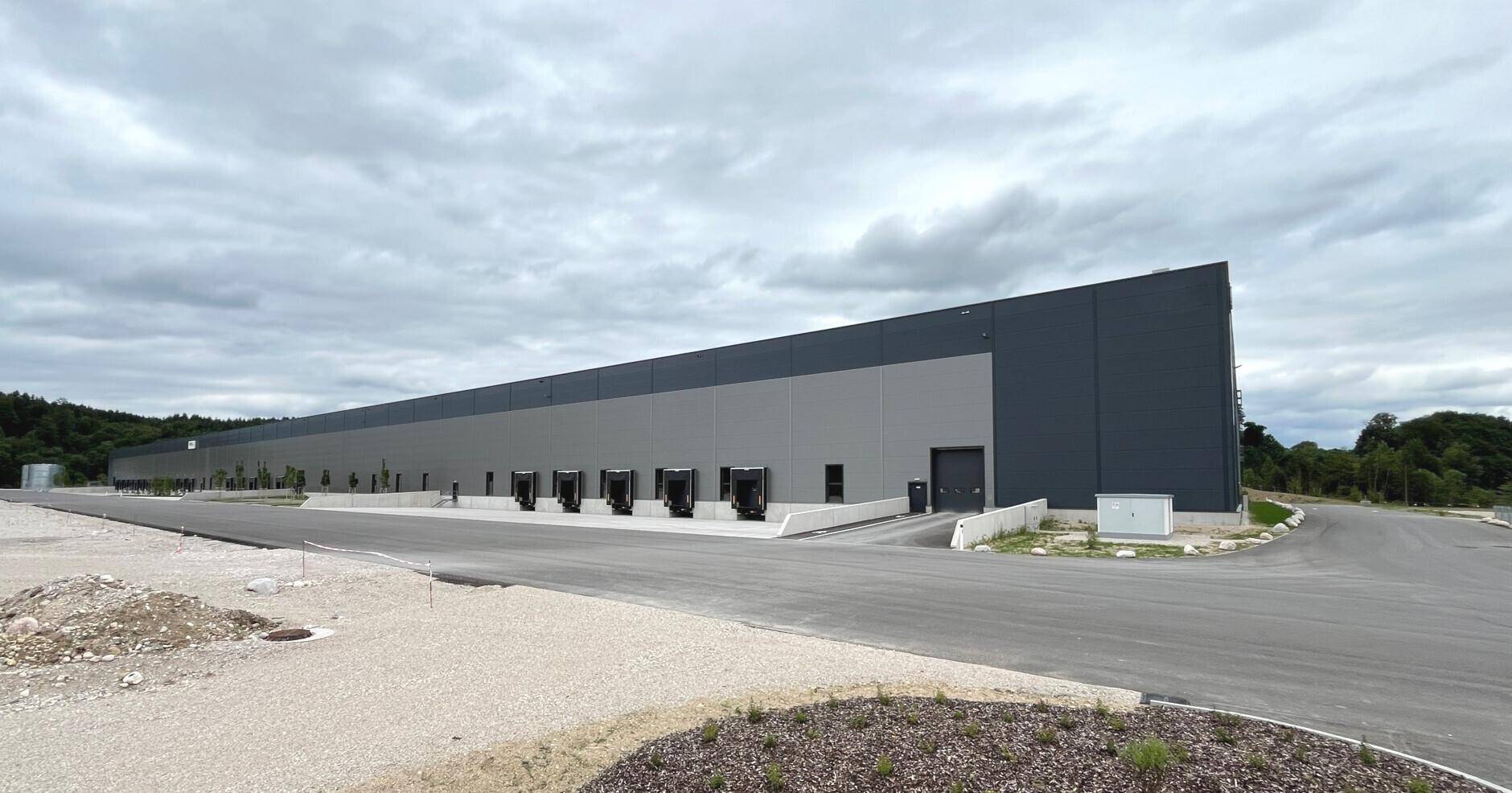 Weitläufige Ansicht eines modernen Logistikzentrums mit zahlreichen Laderampen unter bewölktem Himmel.