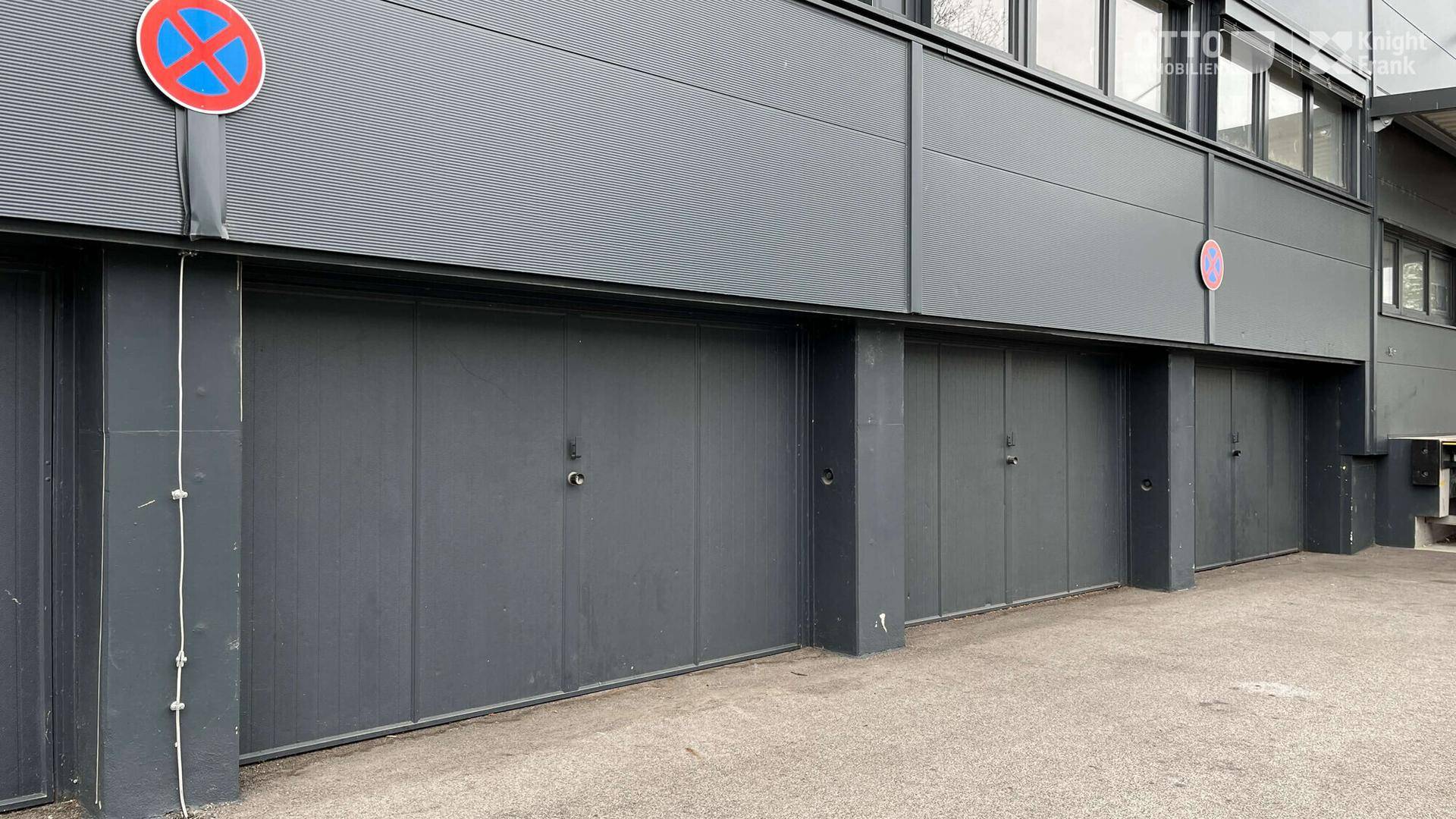 Mehrere Garagentore an der Gebäudefassade, bieten Zugang zu den Park- oder Lagerbereichen.