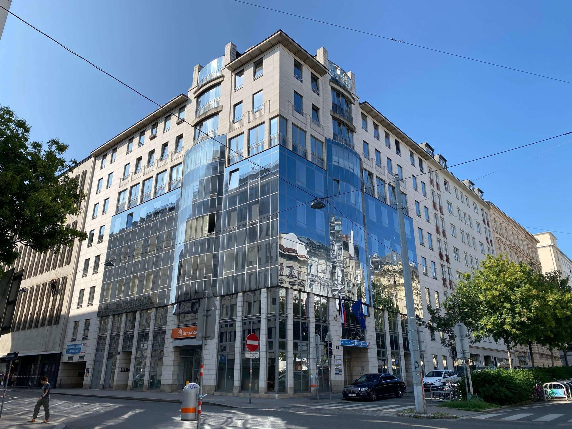Modernes Bürogebäude mit markanter Glasfassade und traditionellen Steinelementen in der Stadt.