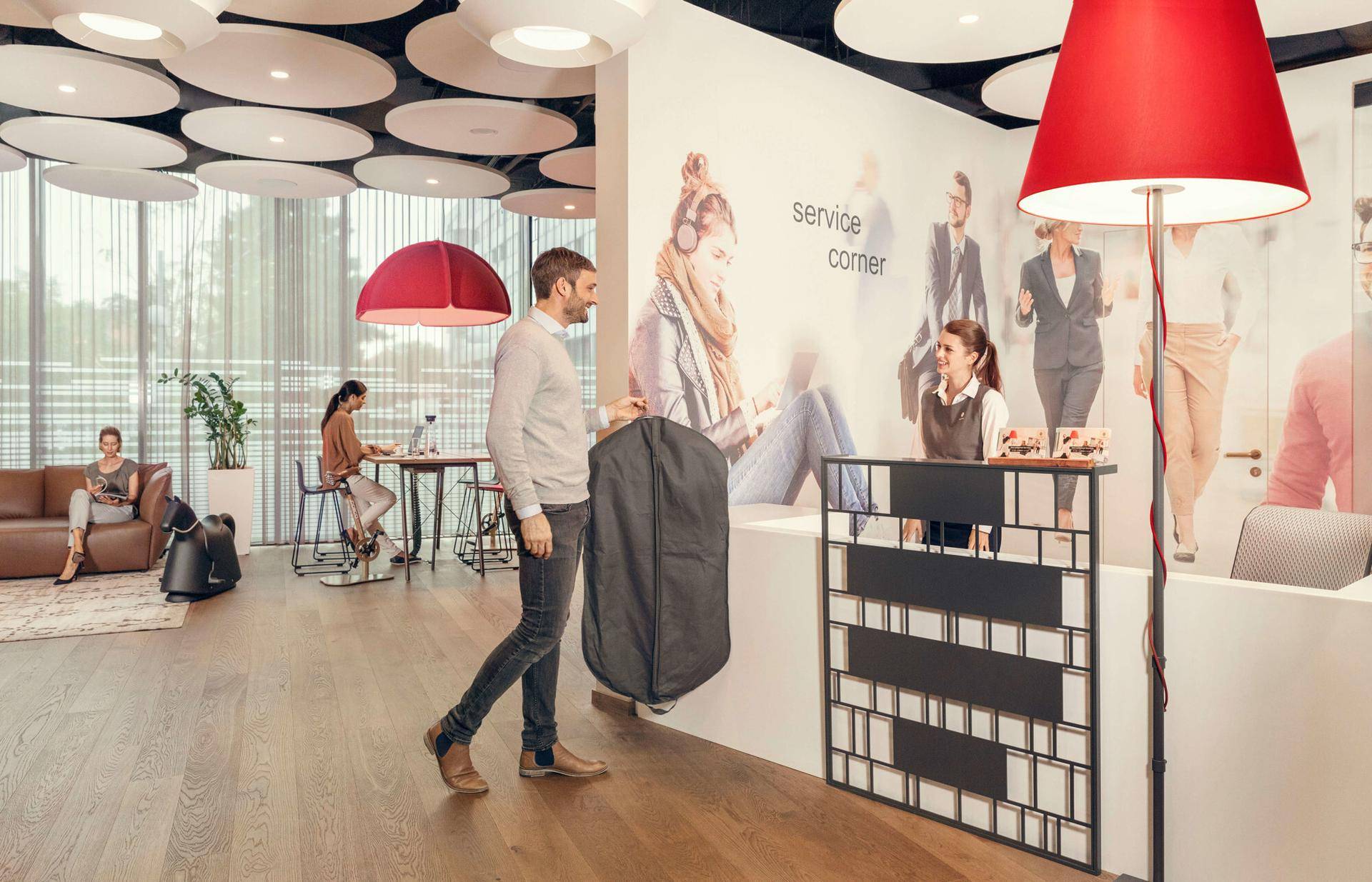 Moderner Empfangsbereich mit Service-Ecke, Holzboden und stilvoller Deckenbeleuchtung, einladend gestaltet.