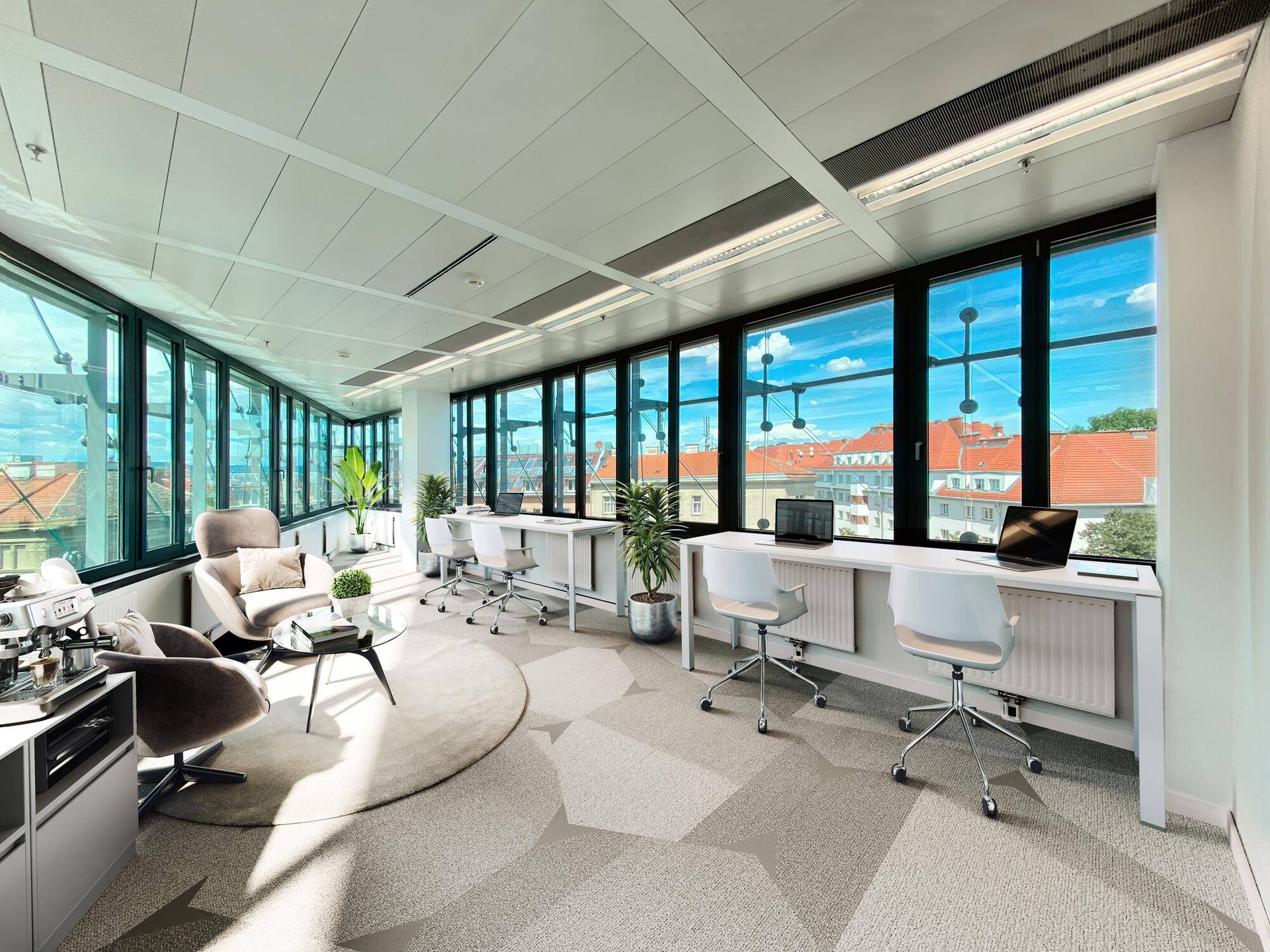 Modernes Büro mit großen Glasfenstern, mehreren Arbeitsplätzen und einer stilvollen Lounge-Ecke.