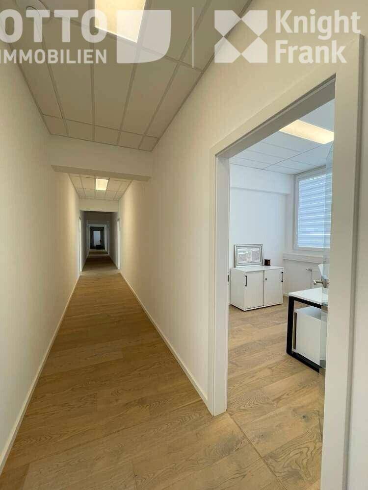 Langer, heller Flur mit Holzboden und Türen zu den angrenzenden Büroräumen.