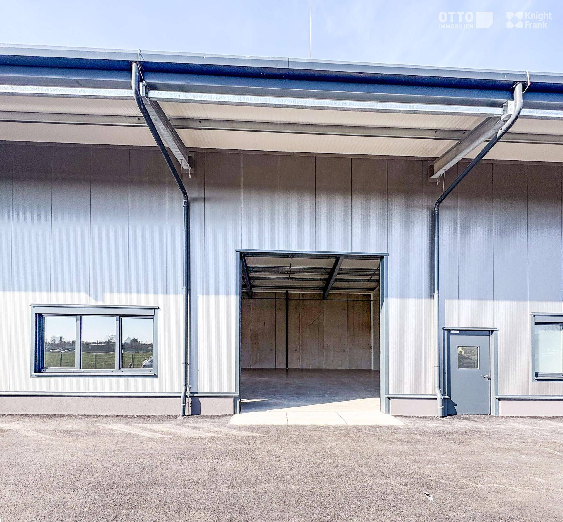 Offenes Rolltor eines modernen Gewerbegebäudes, das den Blick ins Innere der Halle freigibt.