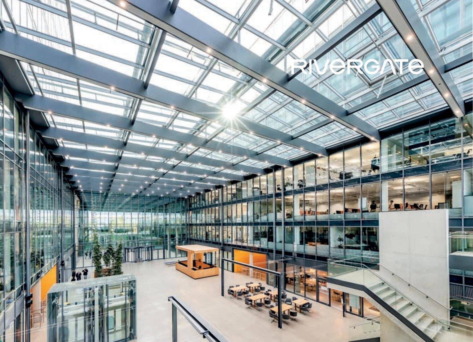 Großzügiges Atrium mit Glasdach und mehreren Etagen, das viel Tageslicht in das moderne Bürogebäude bringt.