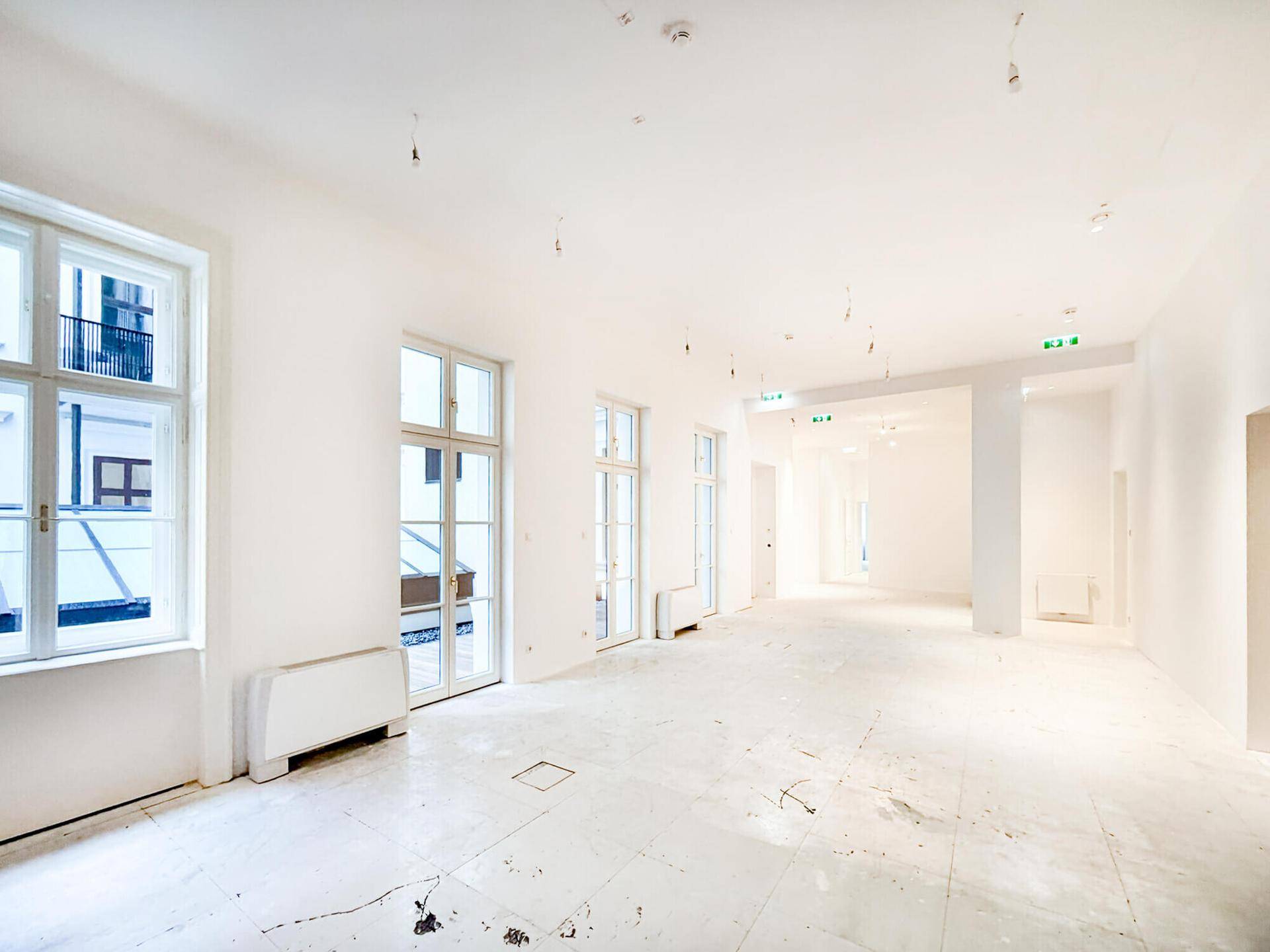 Geräumiger, heller Büroraum mit vielen Fenstern und hohen Decken, bereit für den Ausbau und die Nutzung.
