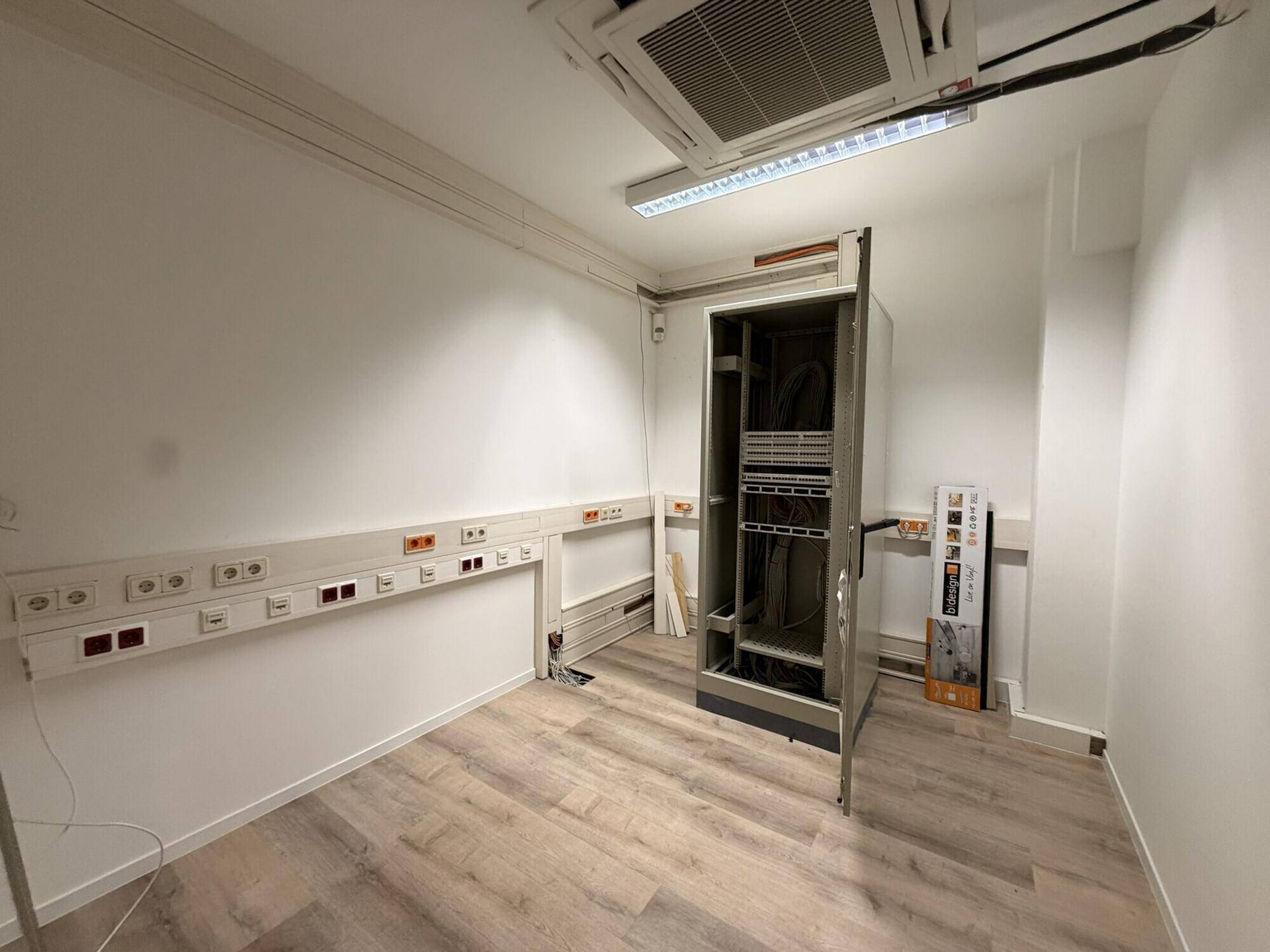 Technischer Raum mit Serverschrank und zahlreichen Steckdosen, ideal für IT-Infrastruktur.