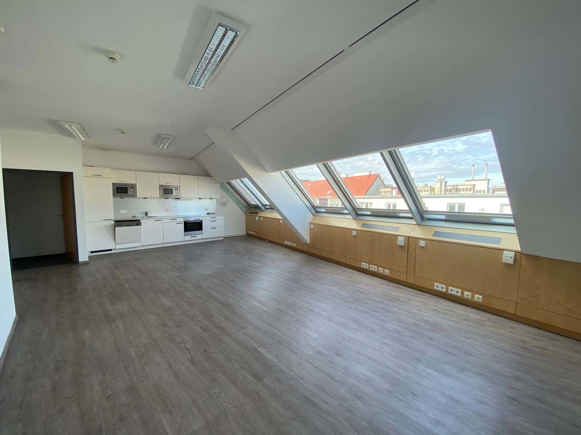 Helles Büro im Dachgeschoss mit integrierter Küchenzeile und großen Dachfenstern.
