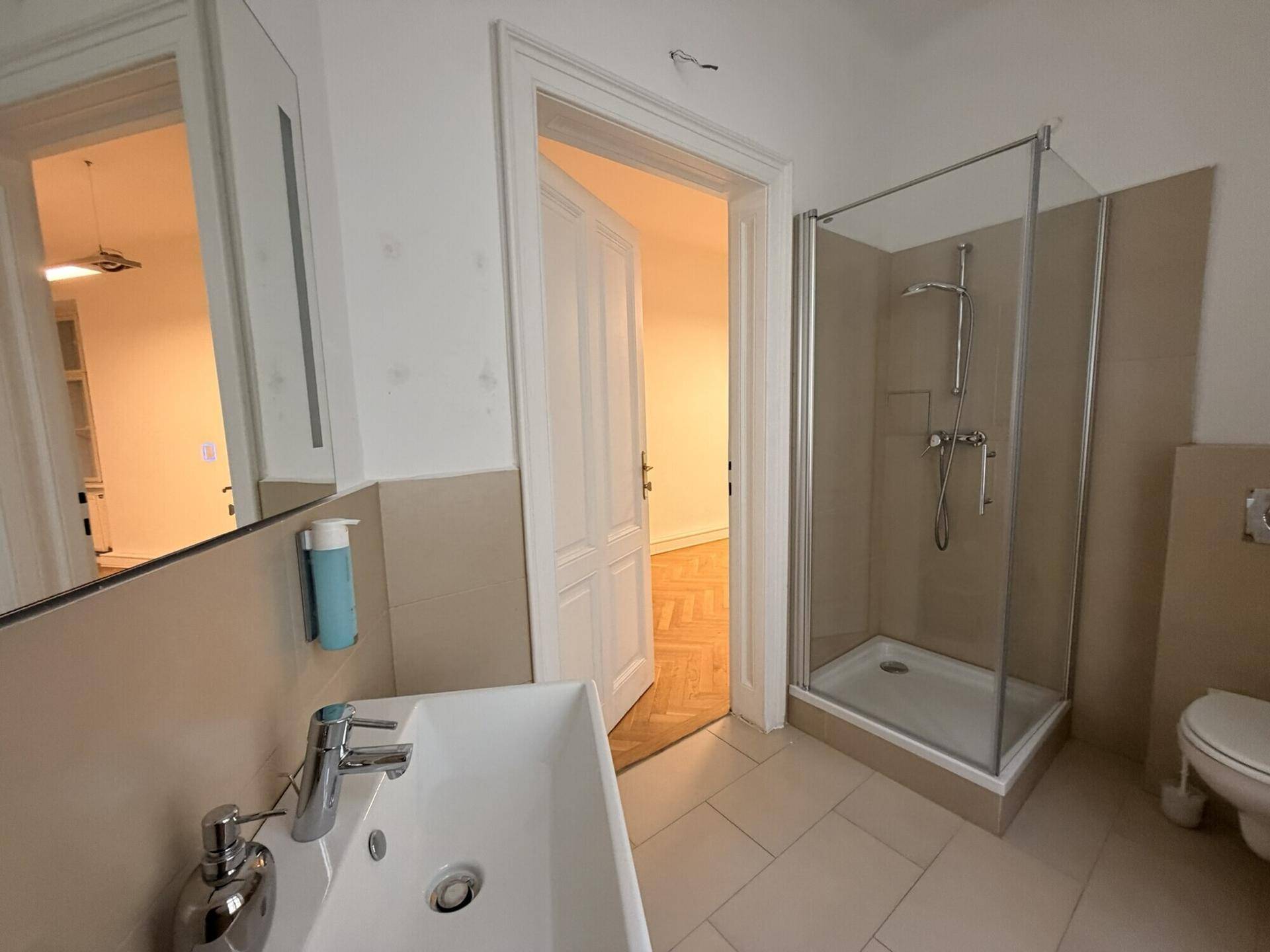 Modernes Badezimmer mit Duschkabine, Waschbecken und Wand-WC, ausgestattet mit hellen Fliesen.