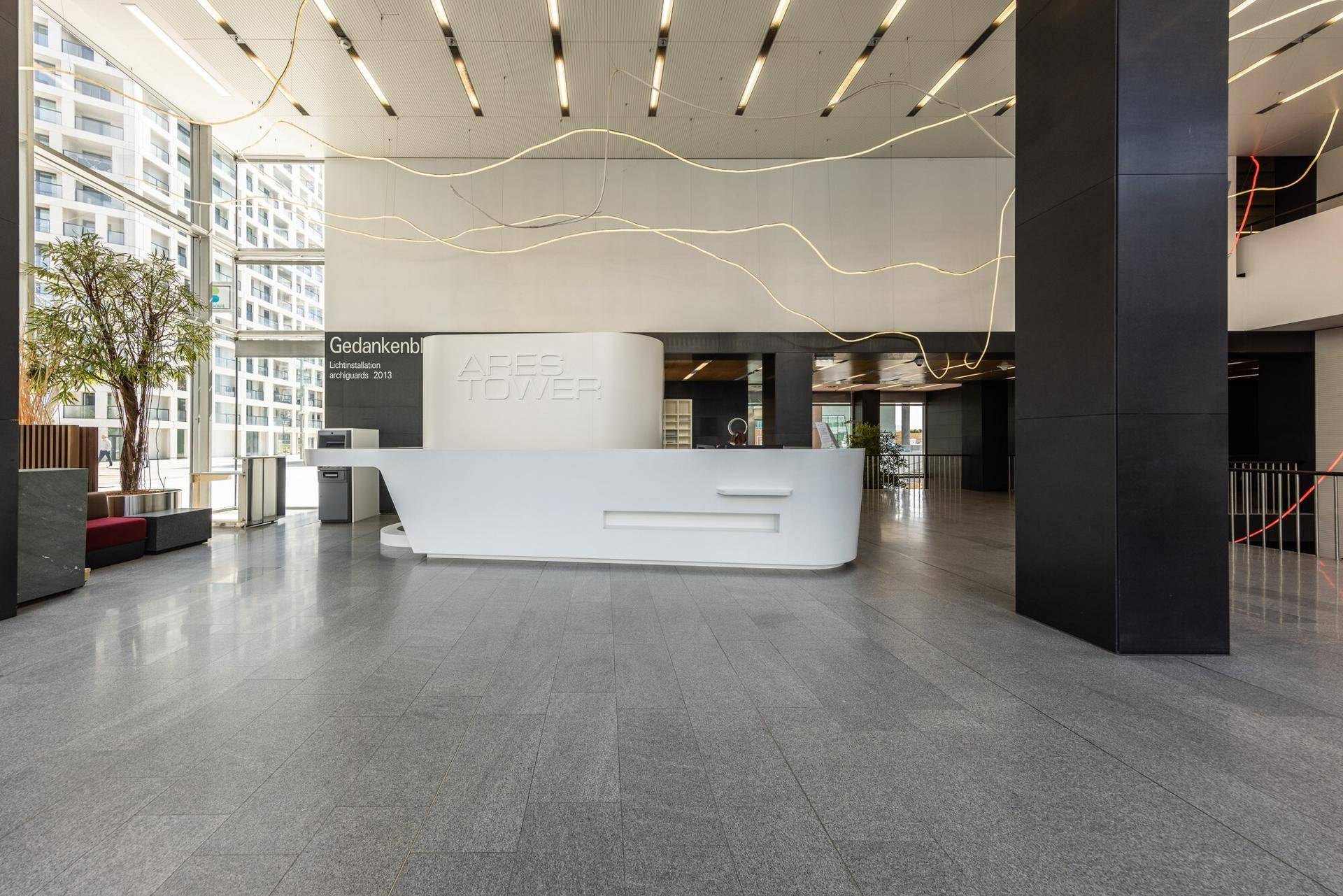 Eindrucksvolle moderne Lobby mit stilvoller Rezeption, Steinboden und hohen Decken, die viel Tageslicht hereinlassen.