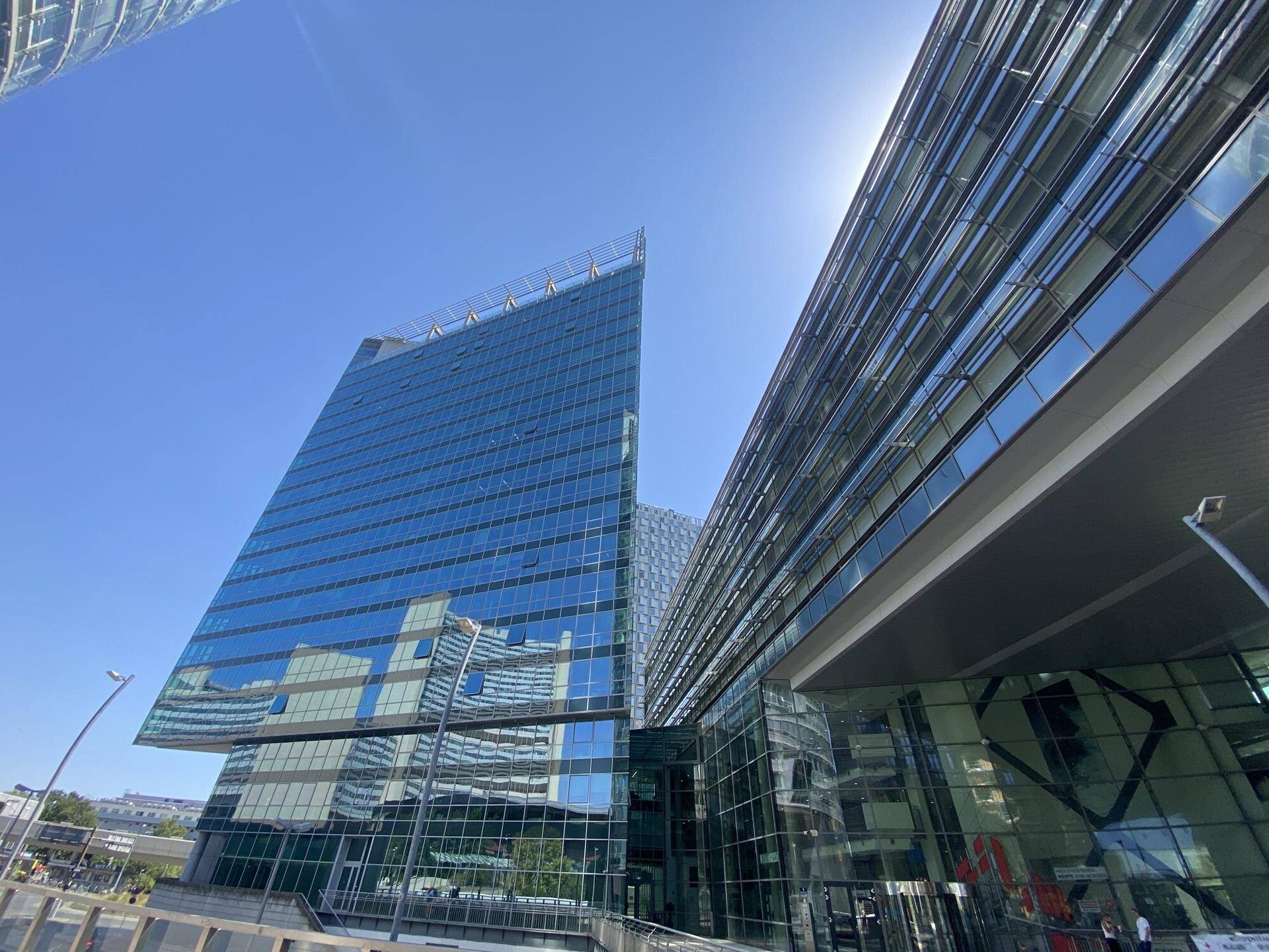 Beeindruckendes modernes Bürogebäude mit spiegelnder Glasfassade unter strahlend blauem Himmel.