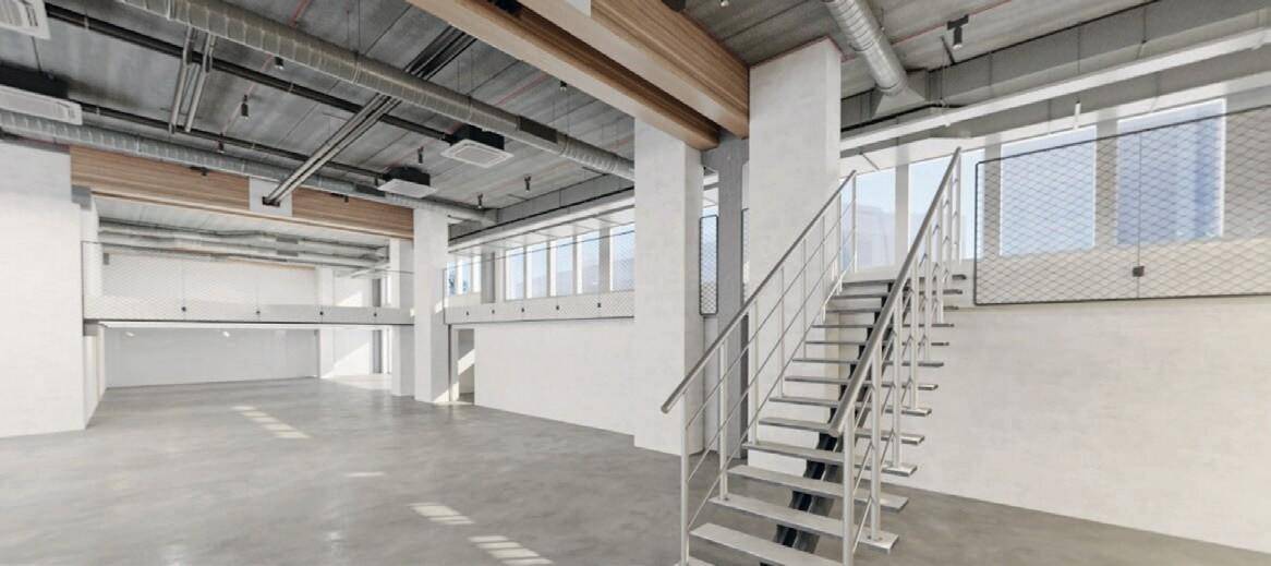 Großer, leerer Gewerberaum mit Betonboden, freiliegenden Rohren an der Decke und einer Metalltreppe.