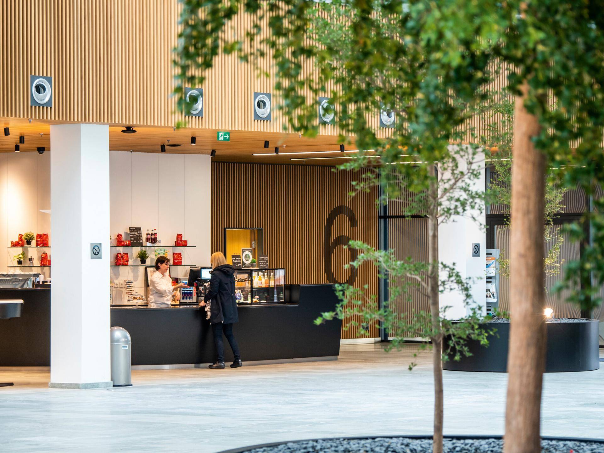 Moderne Café-Bar mit Holzakzenten, einer langen Theke und Sitzgelegenheiten in einem offenen Bereich.