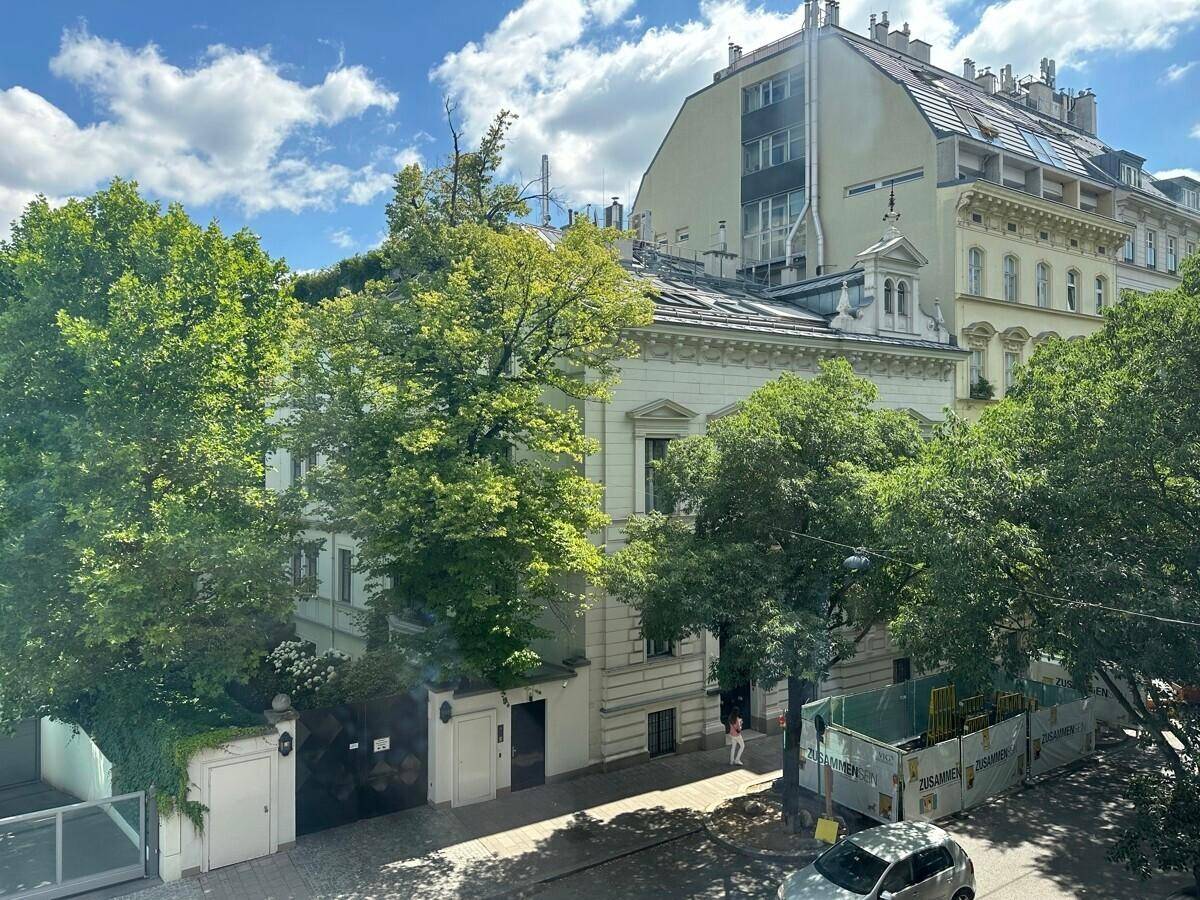 Erhöhter Blick auf eine von Bäumen gesäumte Straße mit historischen Gebäuden und einer Baustelle.