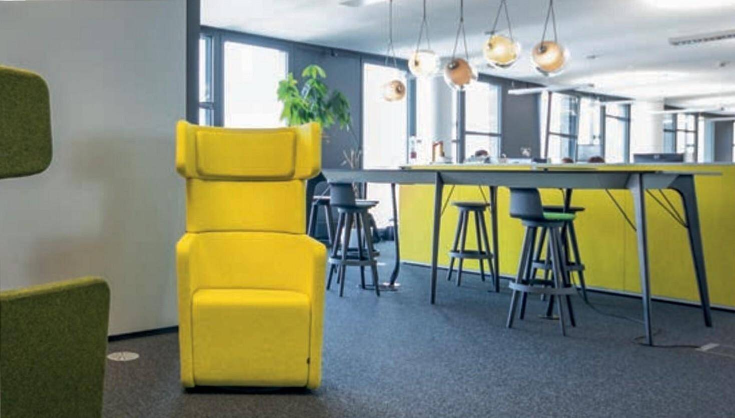 Kreativer Lounge-Bereich mit gelben Akzenten, hohen Hockern und modernen Hängelampen für entspannte Pausen.