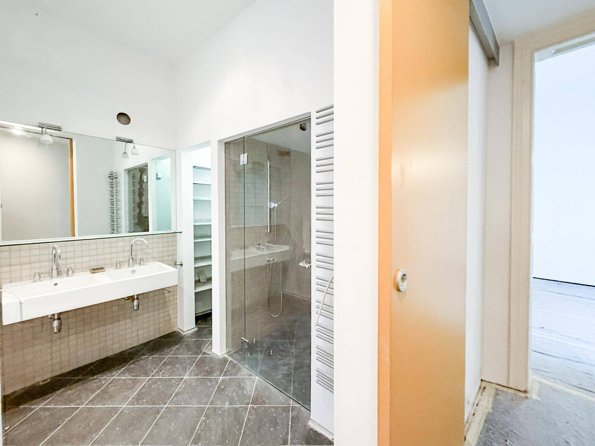 Modernes Badezimmer mit zwei Waschbecken, großem Spiegel und einer begehbaren Glasdusche.