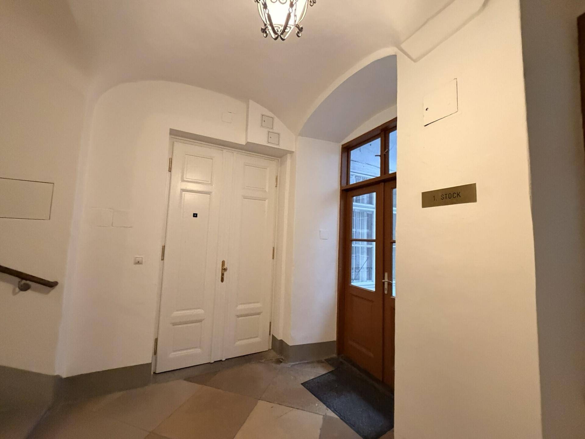 Eingangsbereich mit gewölbter Decke, Holztüren und einer Treppe, die in die oberen Stockwerke führt.