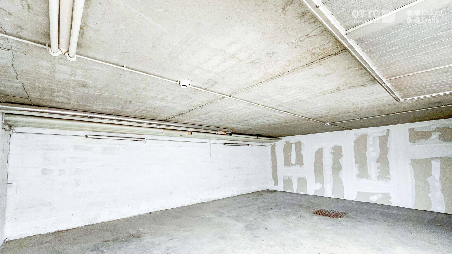 Unfertiger Kellerraum mit Betonboden und sichtbaren Leitungen, ideal als Lagerfläche.