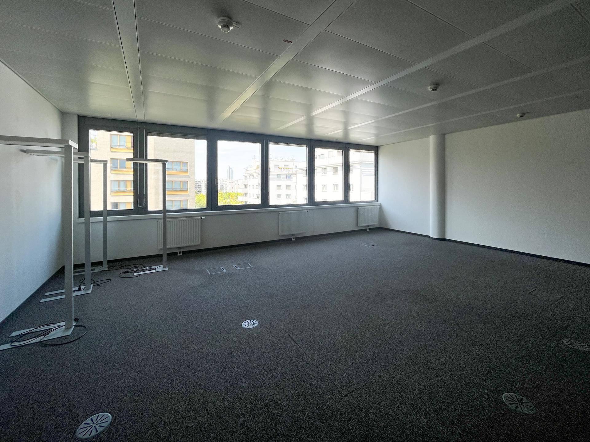 Großes Büro mit Teppichboden, vielen Fenstern und Blick auf die Umgebung, ideal für offene Arbeitsbereiche.