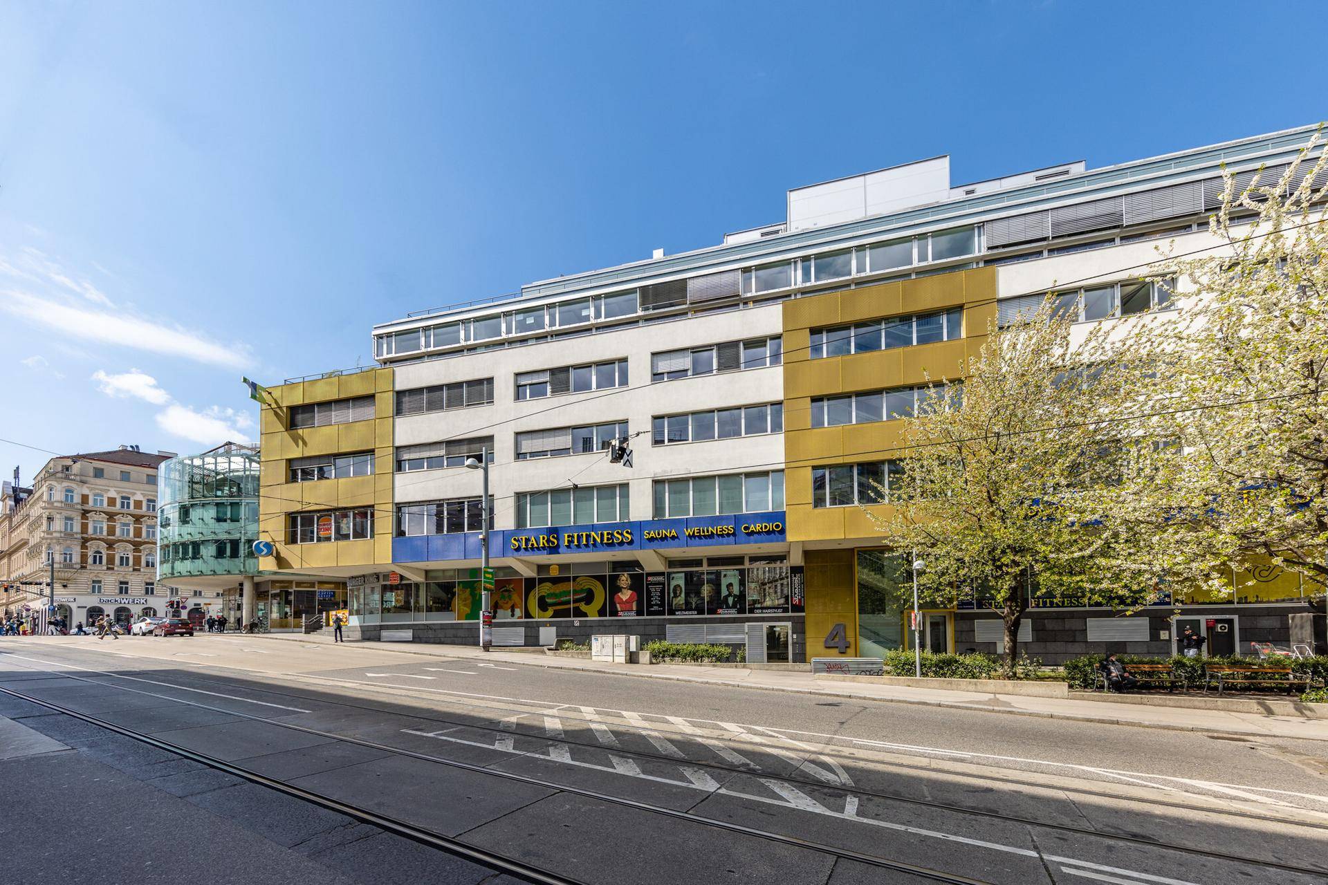 Mehrstöckiges Geschäftsgebäude mit gelber und weißer Fassade an einer belebten Straße.