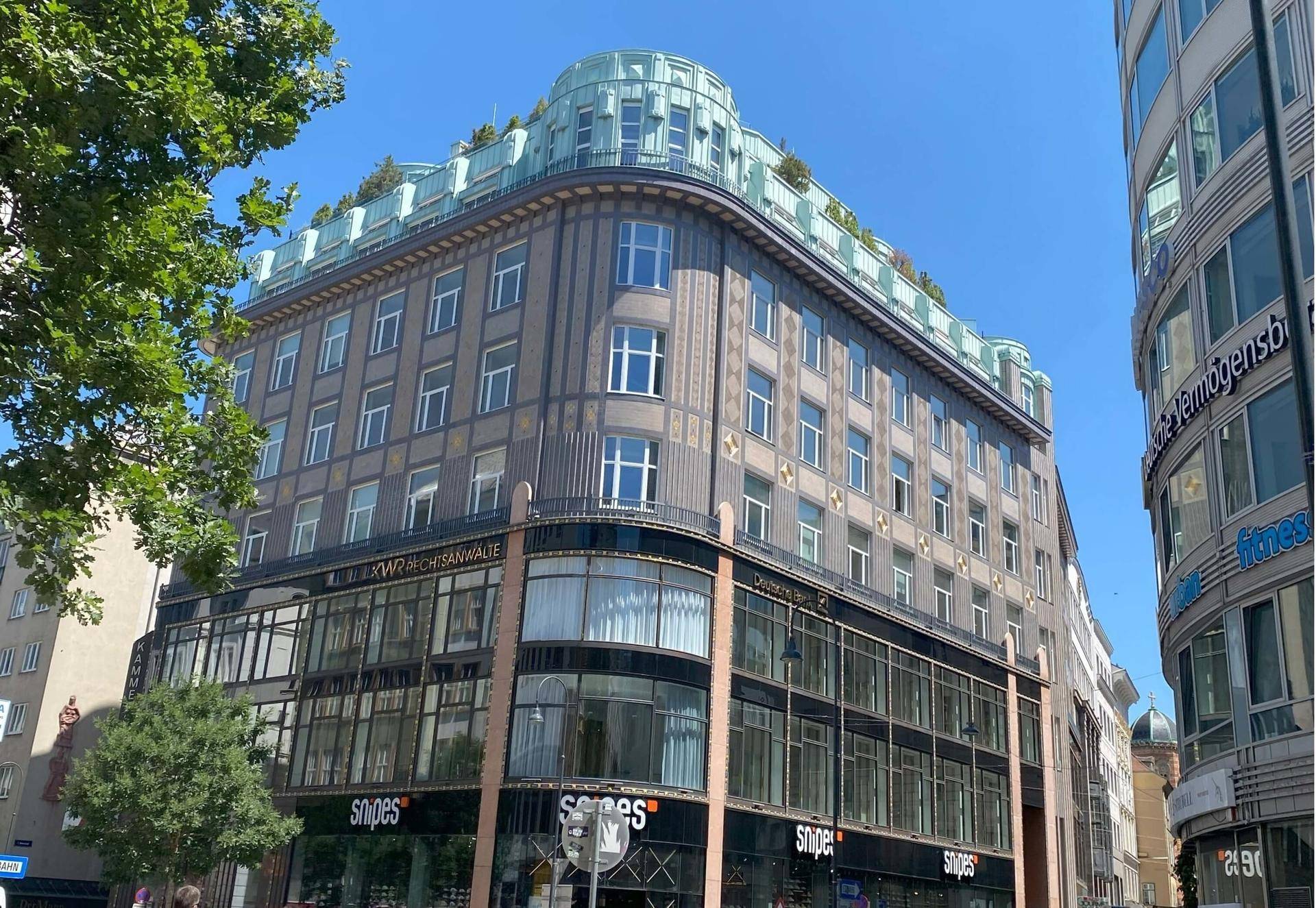 Historisches Gebäude mit markanter Architektur und Geschäften im Erdgeschoss, prägt das Stadtbild mit Eleganz.