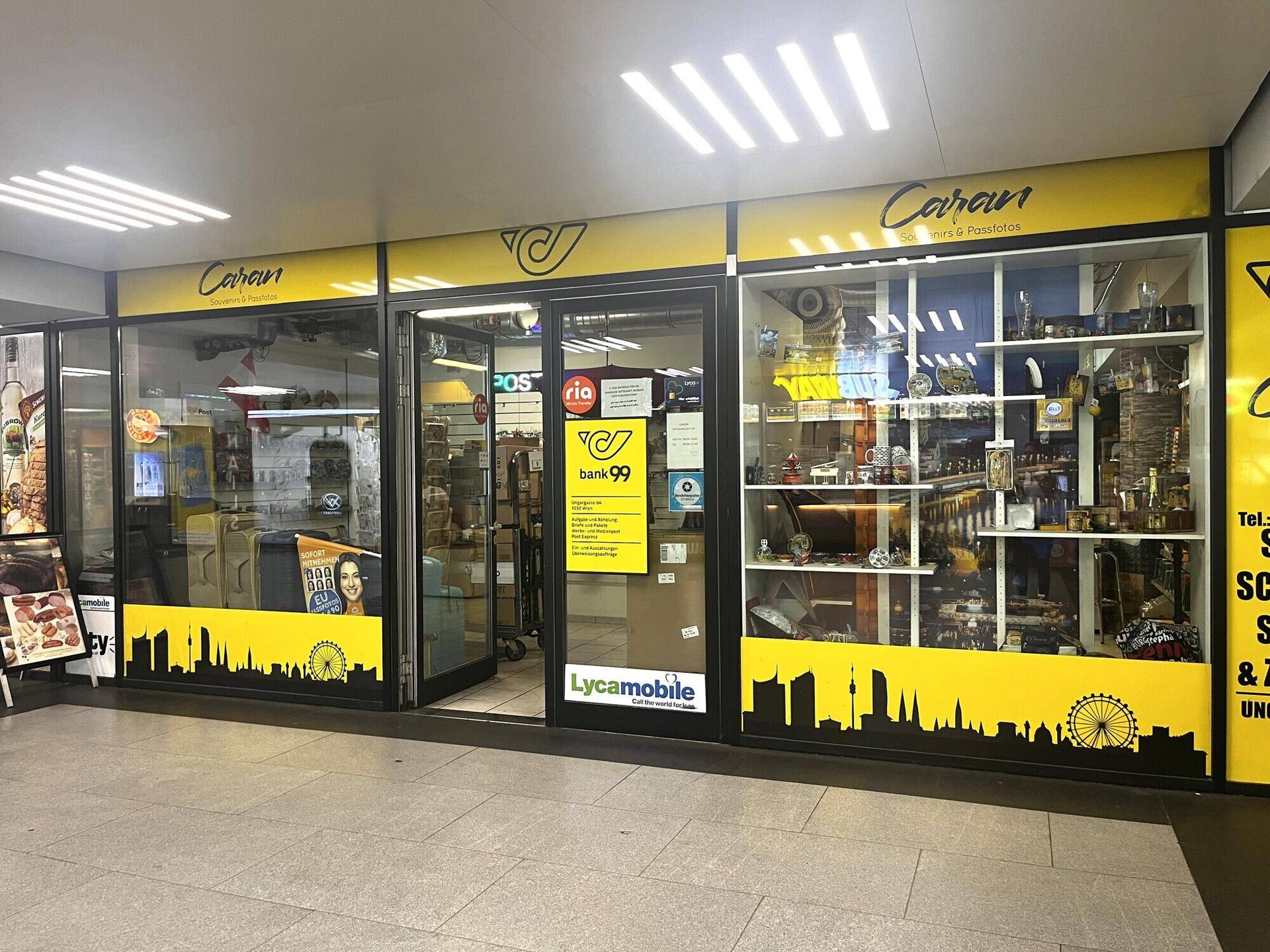 Eingangsbereich eines Ladengeschäfts mit großen Schaufenstern und hellen Deckenleuchten in einem Einkaufszentrum.