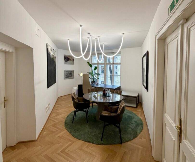 Moderner Essbereich mit rundem Tisch, bequemen Stühlen und auffälliger Deckenbeleuchtung, auf elegantem Parkettboden.