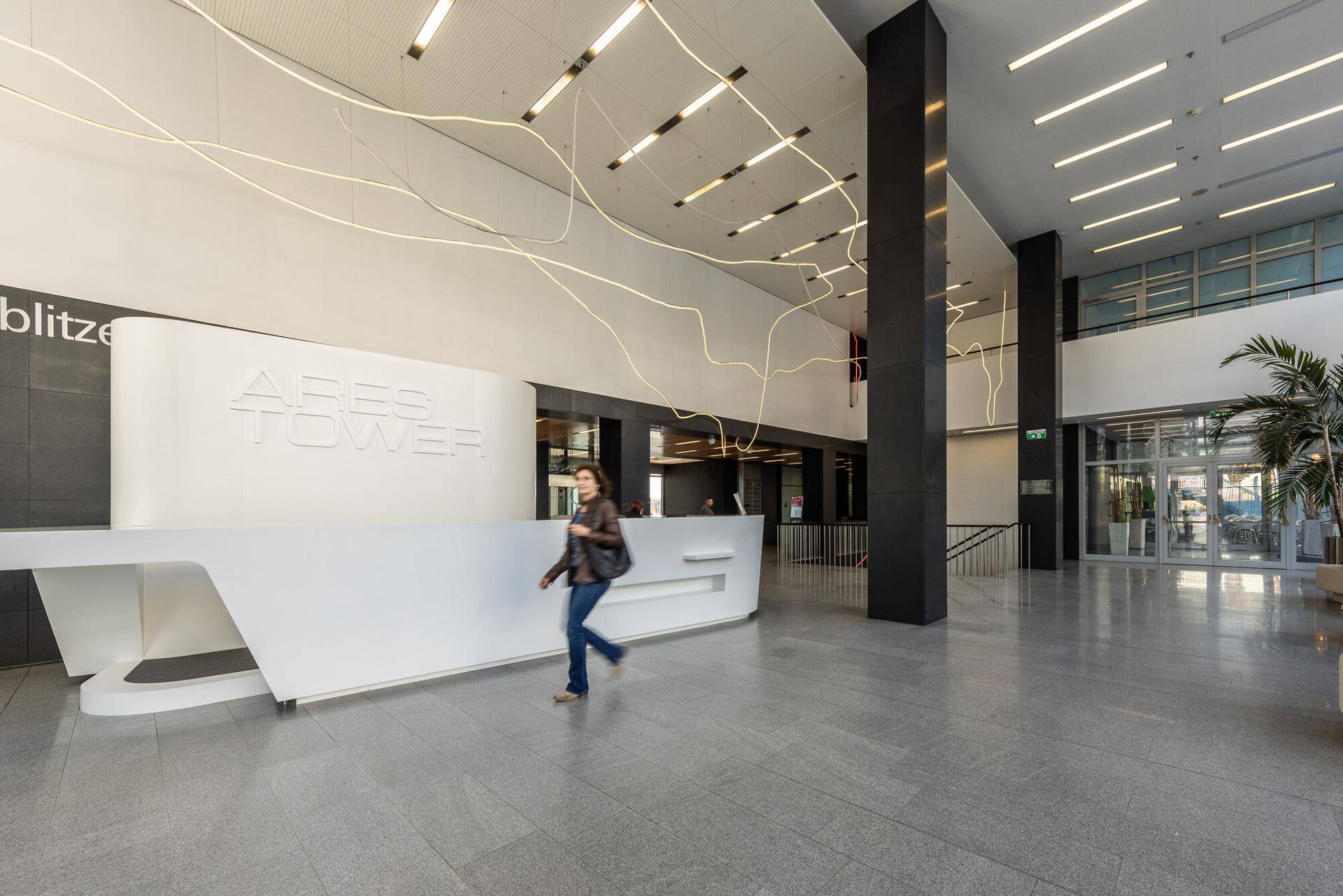 Elegante und helle Lobby mit moderner Rezeption, Glasfassade und Granitboden im Aries Tower.