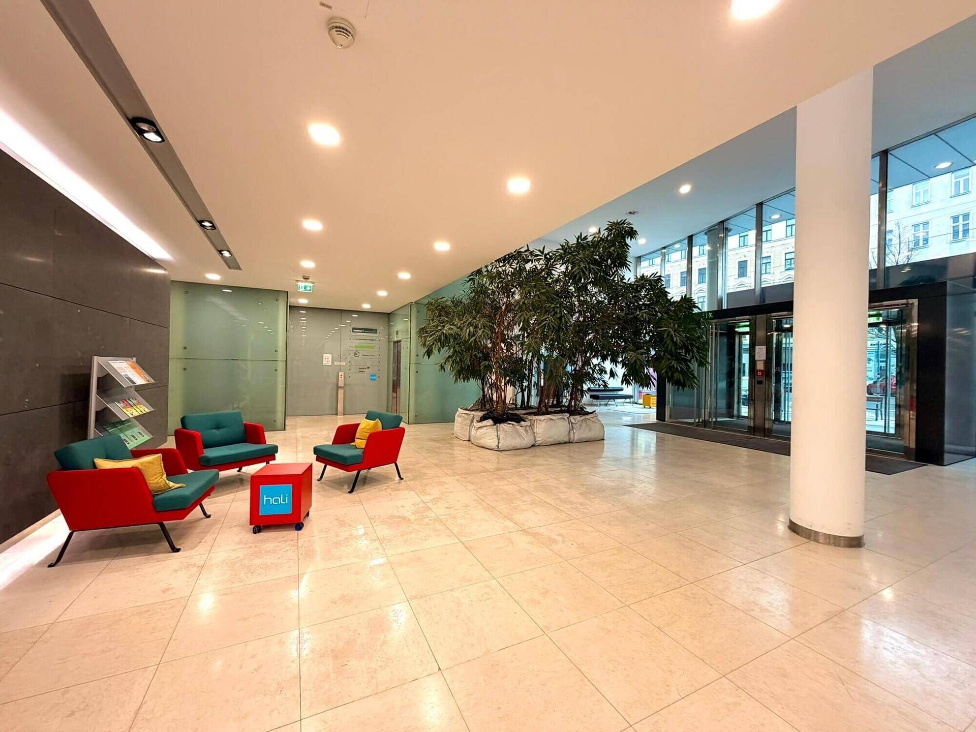 Helle und moderne Lobby mit bequemen Sitzgelegenheiten, Pflanzen und großformatigen Fliesen.