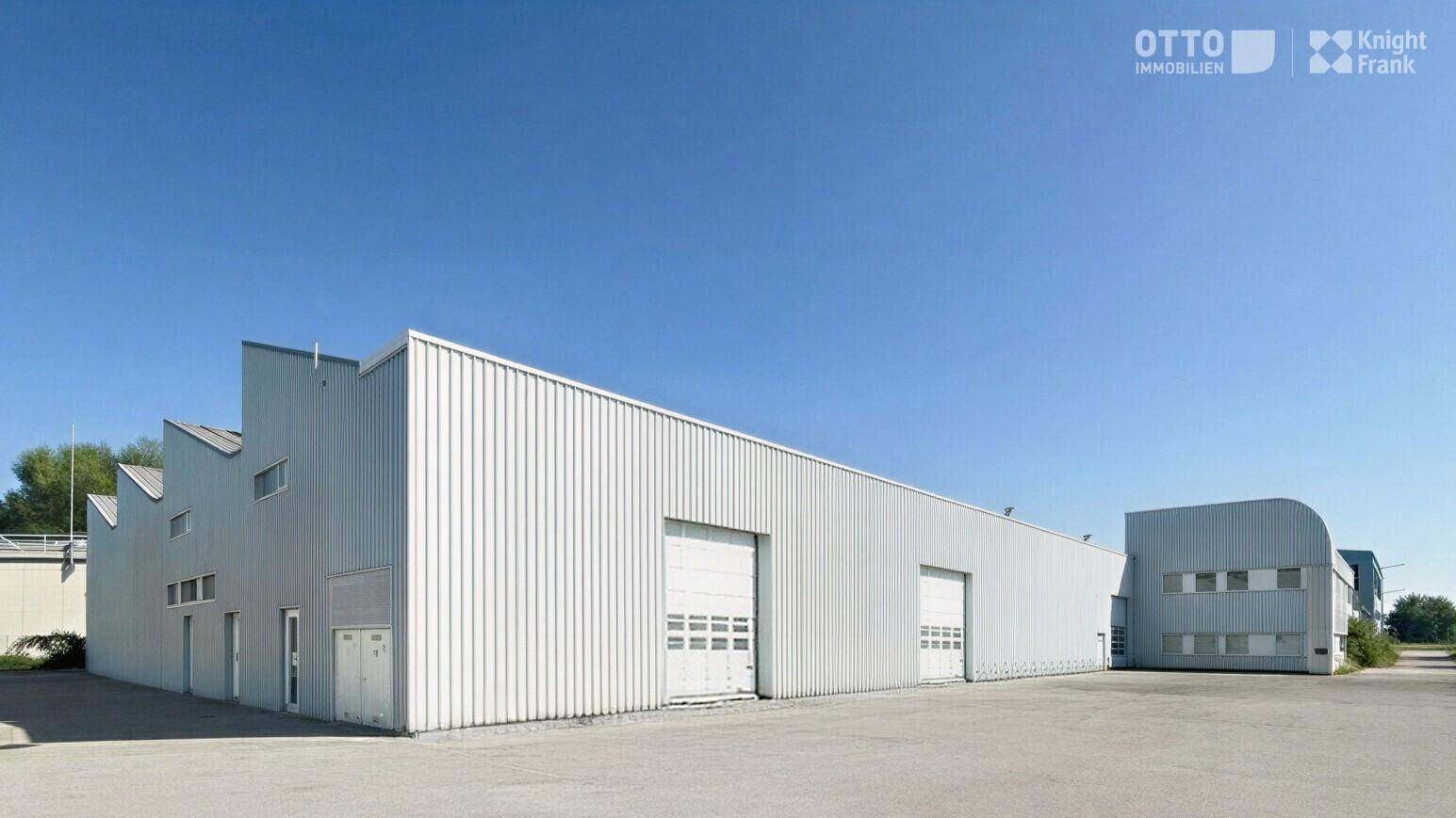 Lange Außenansicht eines Industriegebäudes mit mehreren Rolltoren und Wellblechfassade unter blauem Himmel.