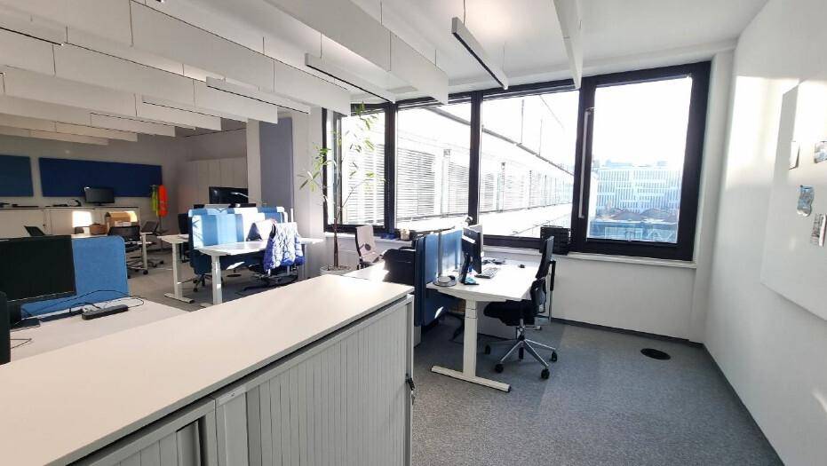 Helles Einzelbüro mit modernen Schreibtischen, Bürostühlen und großen Fenstern mit Blick nach draußen.