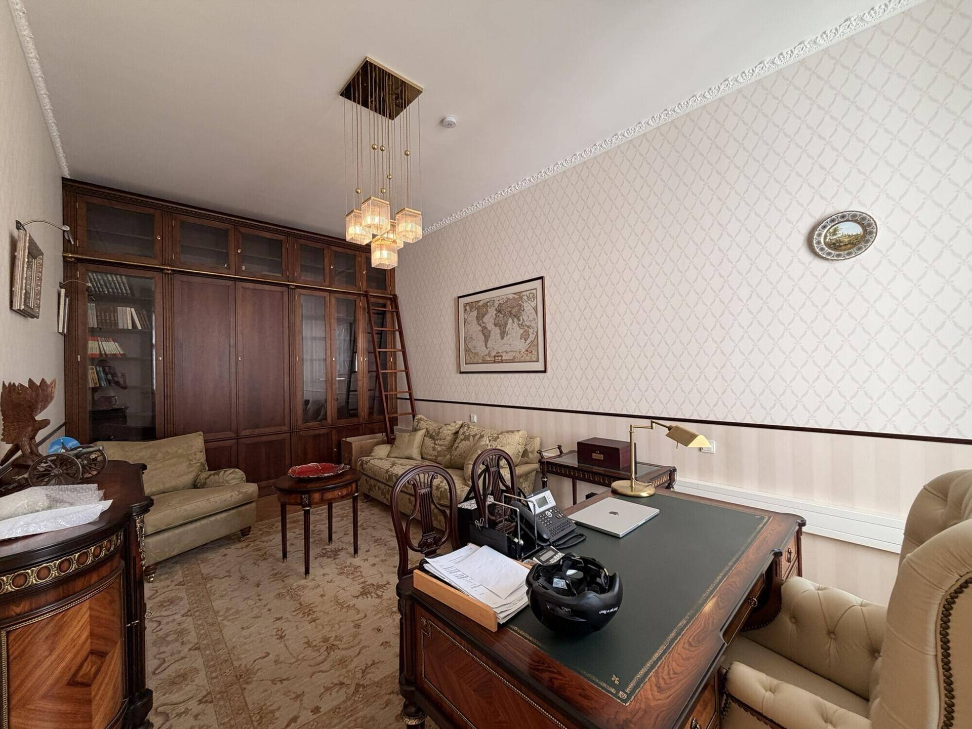 Elegantes Büro mit dunklen Holzmöbeln, Bücherregal und einem großen Schreibtisch in klassischem Stil.