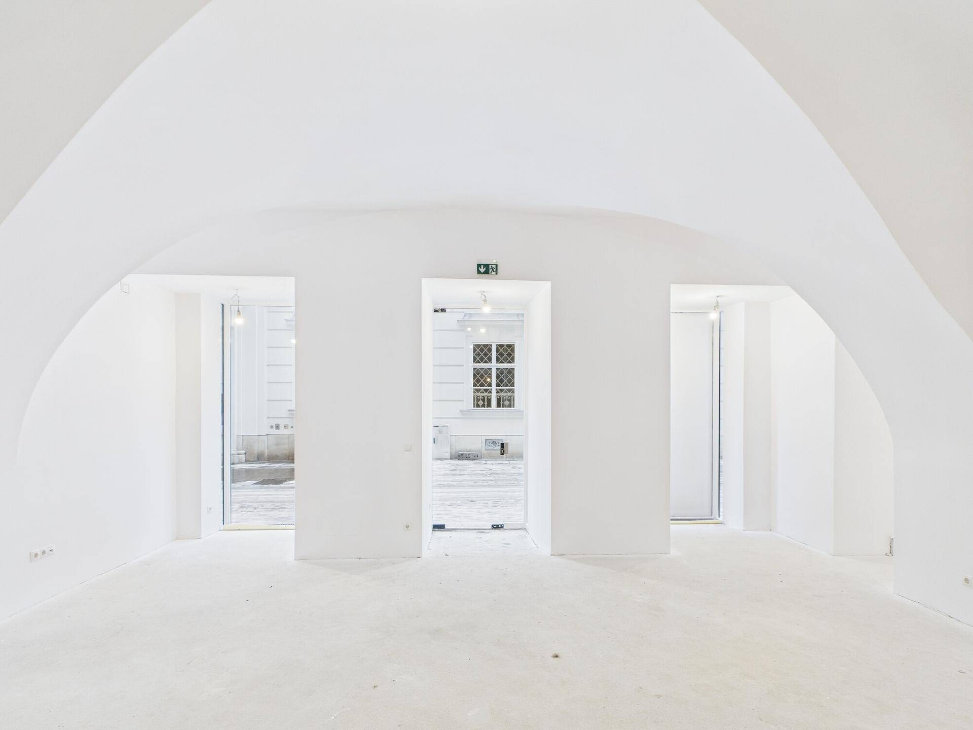 Heller, leerer Verkaufsraum mit markanten Gewölbedecken und großen Fensteröffnungen zum Innenhof.