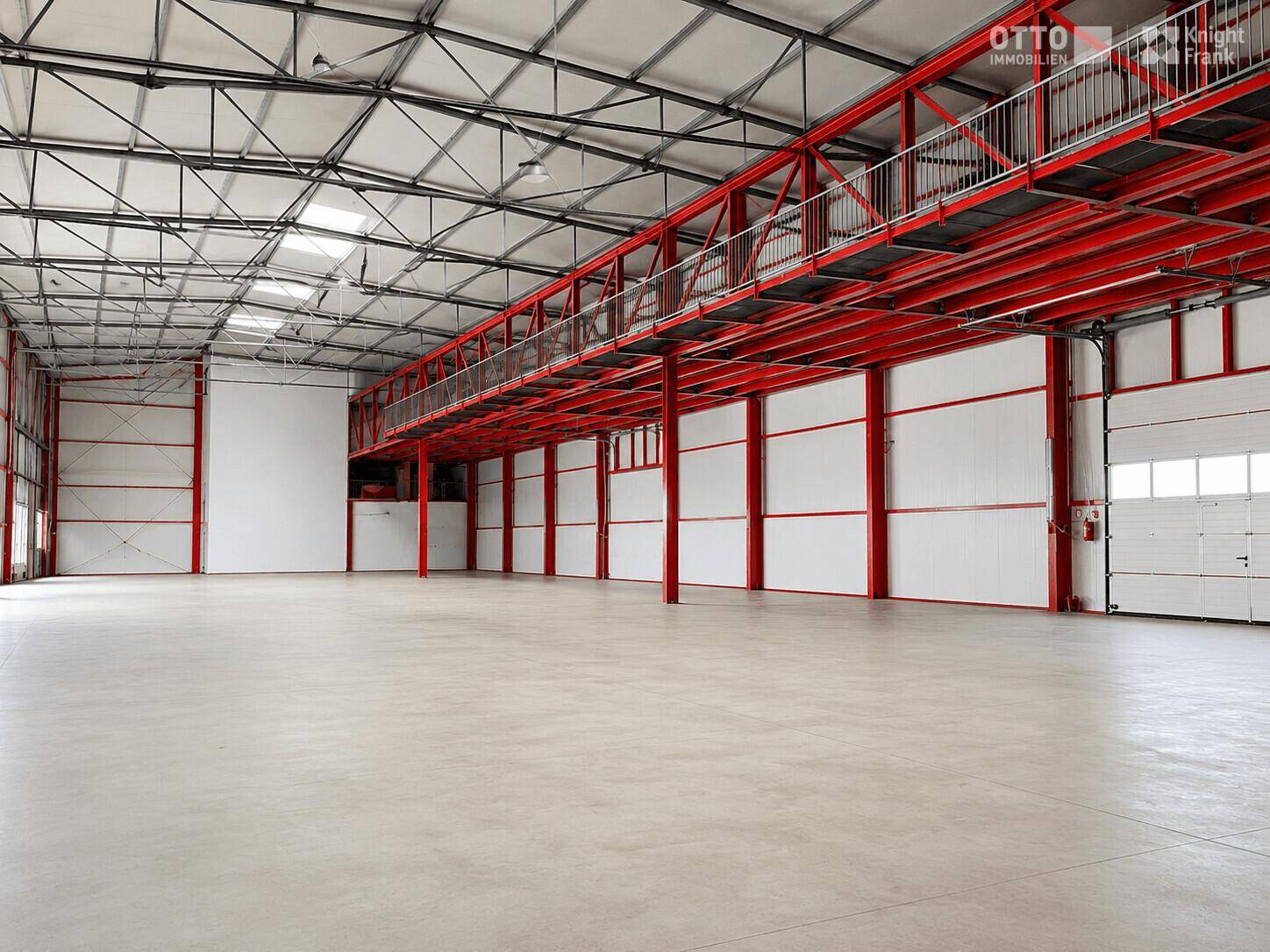 Helle Industriehalle mit roter Stahlkonstruktion, Zwischengeschoss und großen Fenstern für viel Tageslicht.