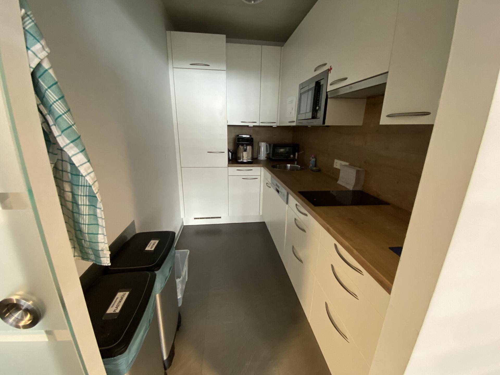 Kleine, funktionale Küchenzeile mit weißen Schränken und Holz-Arbeitsplatte.