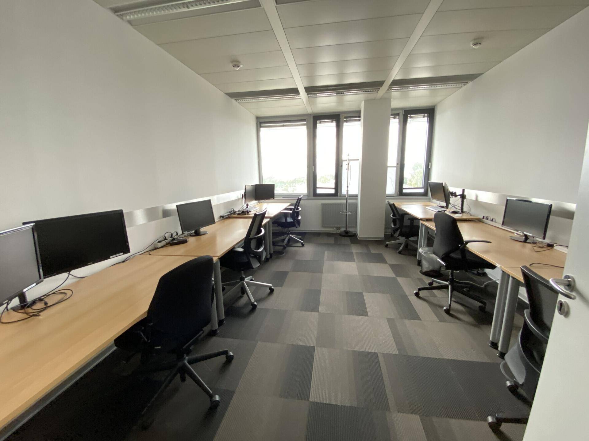 Modernes Büro mit flexiblen Arbeitsplätzen und guter Beleuchtung durch die Fensterfront.