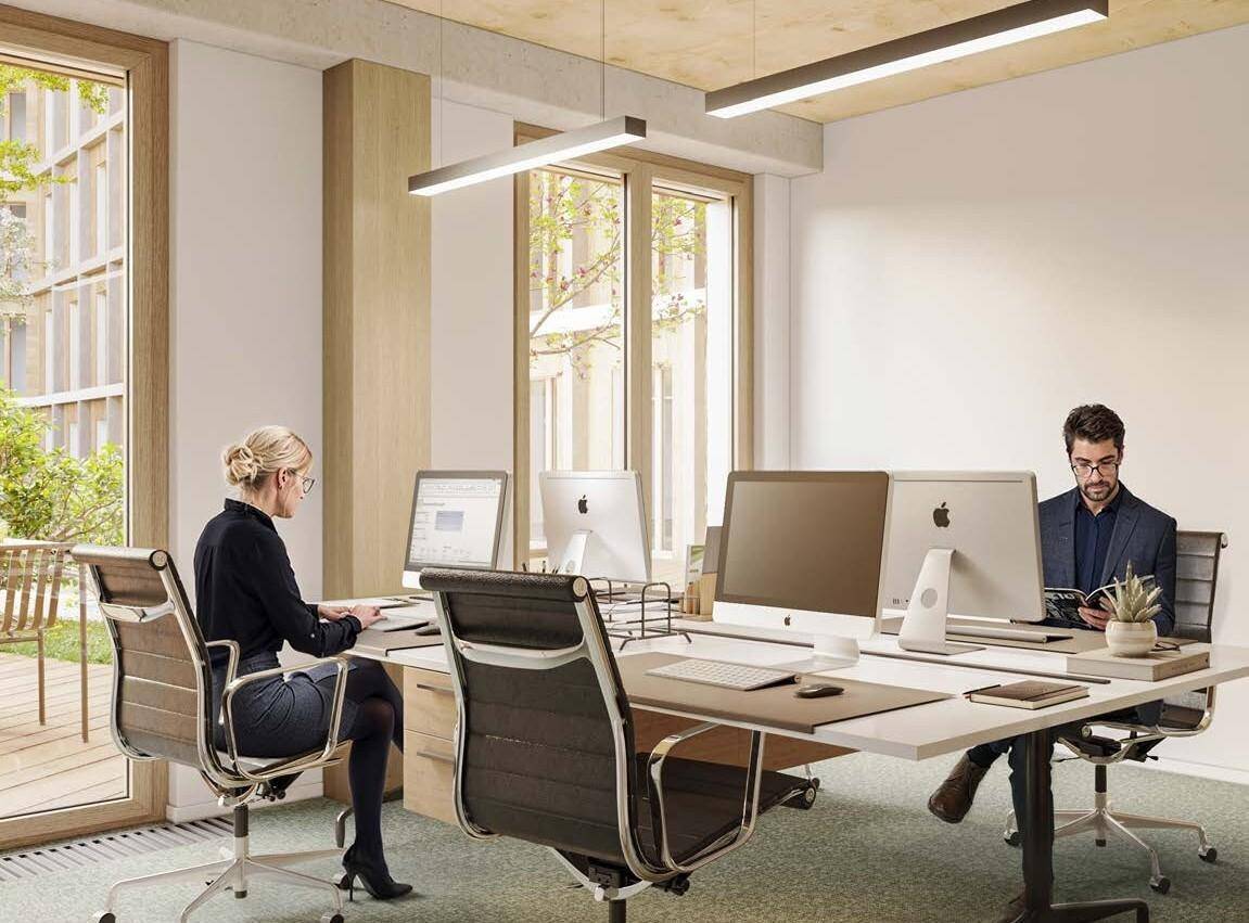 Offener Bürobereich mit mehreren Arbeitsplätzen, großen Fenstern und Blick auf den Innenhof.