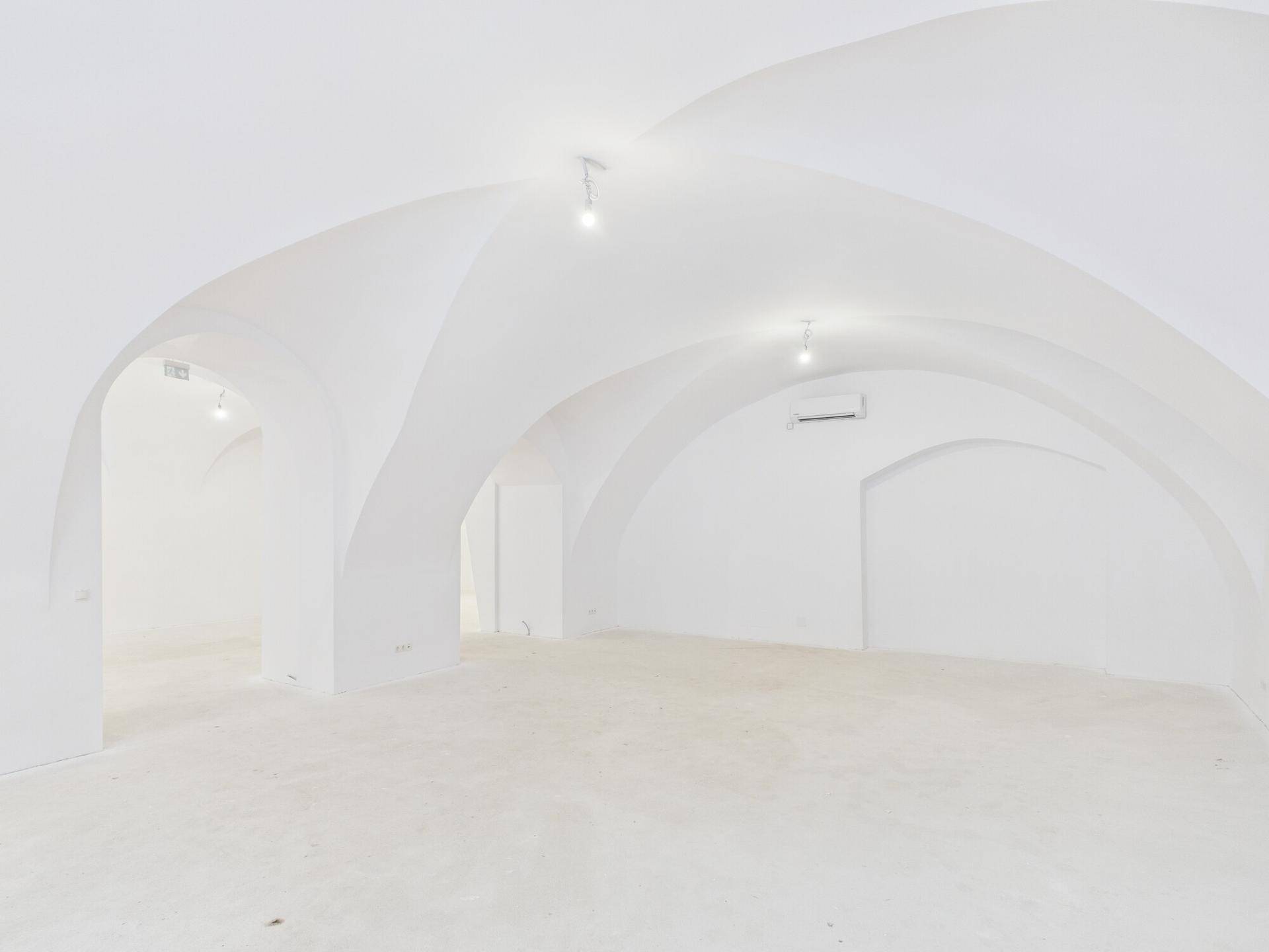 Geräumiger, leerer Innenraum mit eleganten Gewölbedecken und installierter Klimaanlage, bereit zur Nutzung.