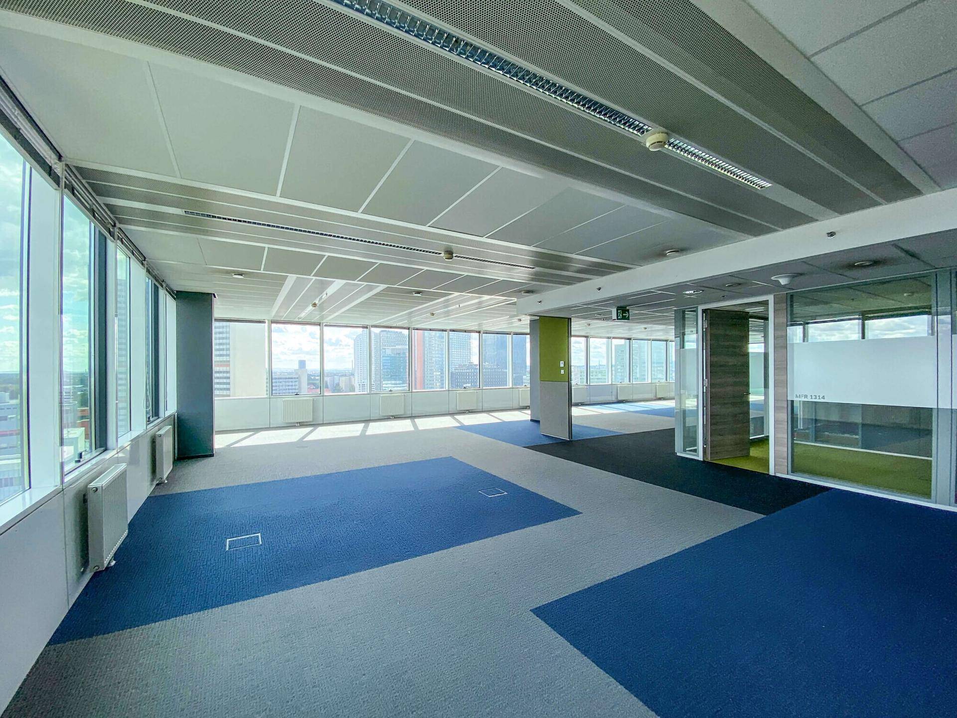 Großes, offenes Büro mit Teppichboden, Glaswänden und weitem Stadtblick.
