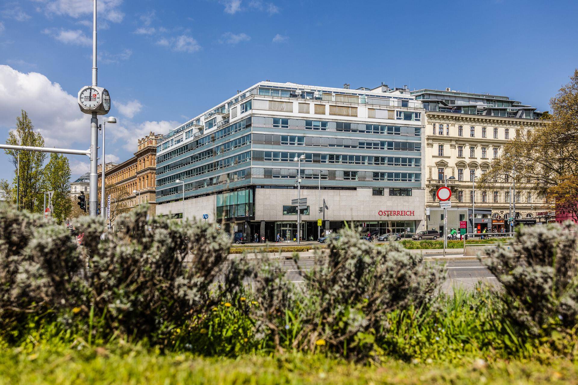 Geschäftsgebäude mit zeitgenössischer Architektur, großen Fenstern und gepflegten Sträuchern im Vordergrund.