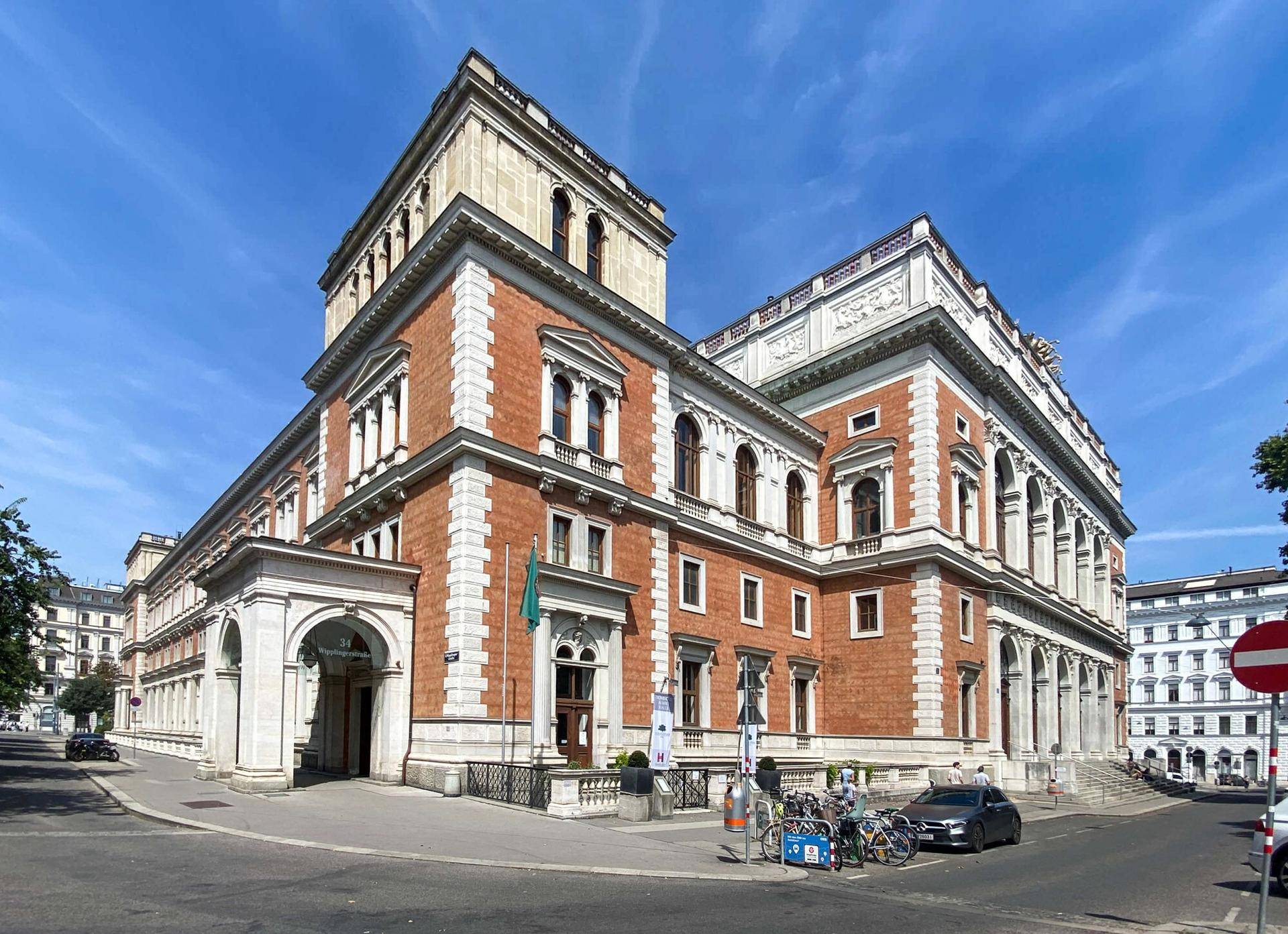 Historisches Gebäude mit beeindruckender Architektur, roten Fassaden und eleganten Verzierungen unter blauem Himmel.