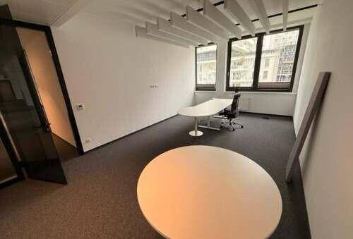 Einzelbüro mit Teppichboden, modernen Möbeln und großen Fenstern, bietet eine ruhige Arbeitsumgebung.