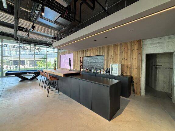 Moderne Bar mit dunklen Schränken, Holzarbeitsplatte und rustikaler Holzverkleidung an der Wand.