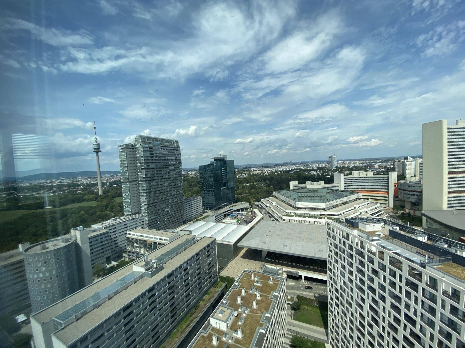 Panoramablick auf die Stadt mit Hochhäusern, Fluss und Brücken unter einem bewölkten Himmel.