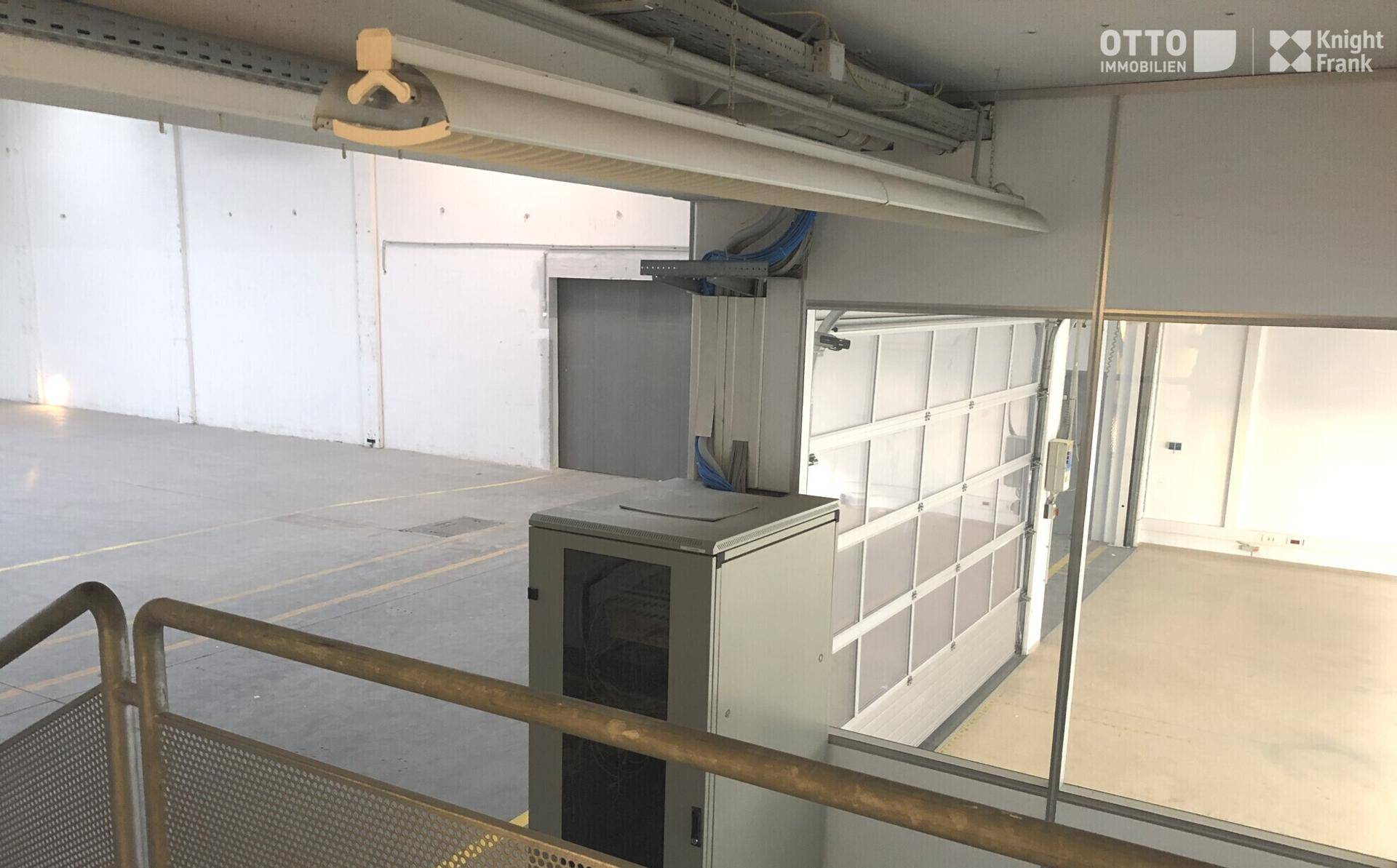 Blick von einer erhöhten Plattform auf die Lagerhalle mit großem Tor und technischer Infrastruktur.