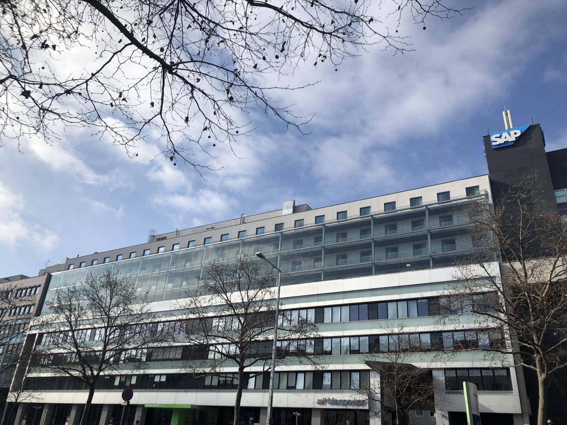 Großes modernes Bürogebäude mit Glasfassade und dem SAP-Logo unter einem bewölkten Himmel.